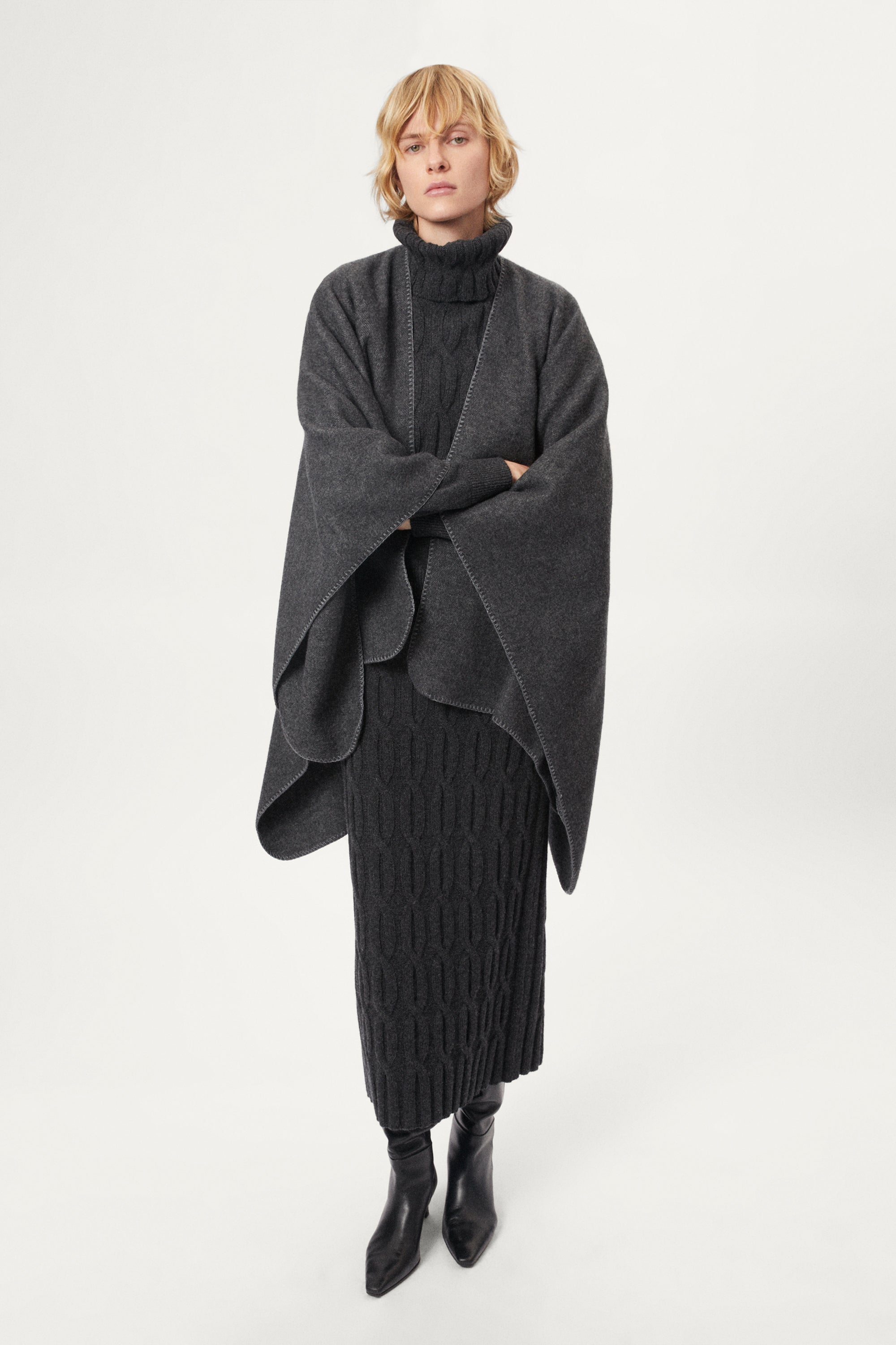 woman wearing a gray poncho over a grey outfit on a white background