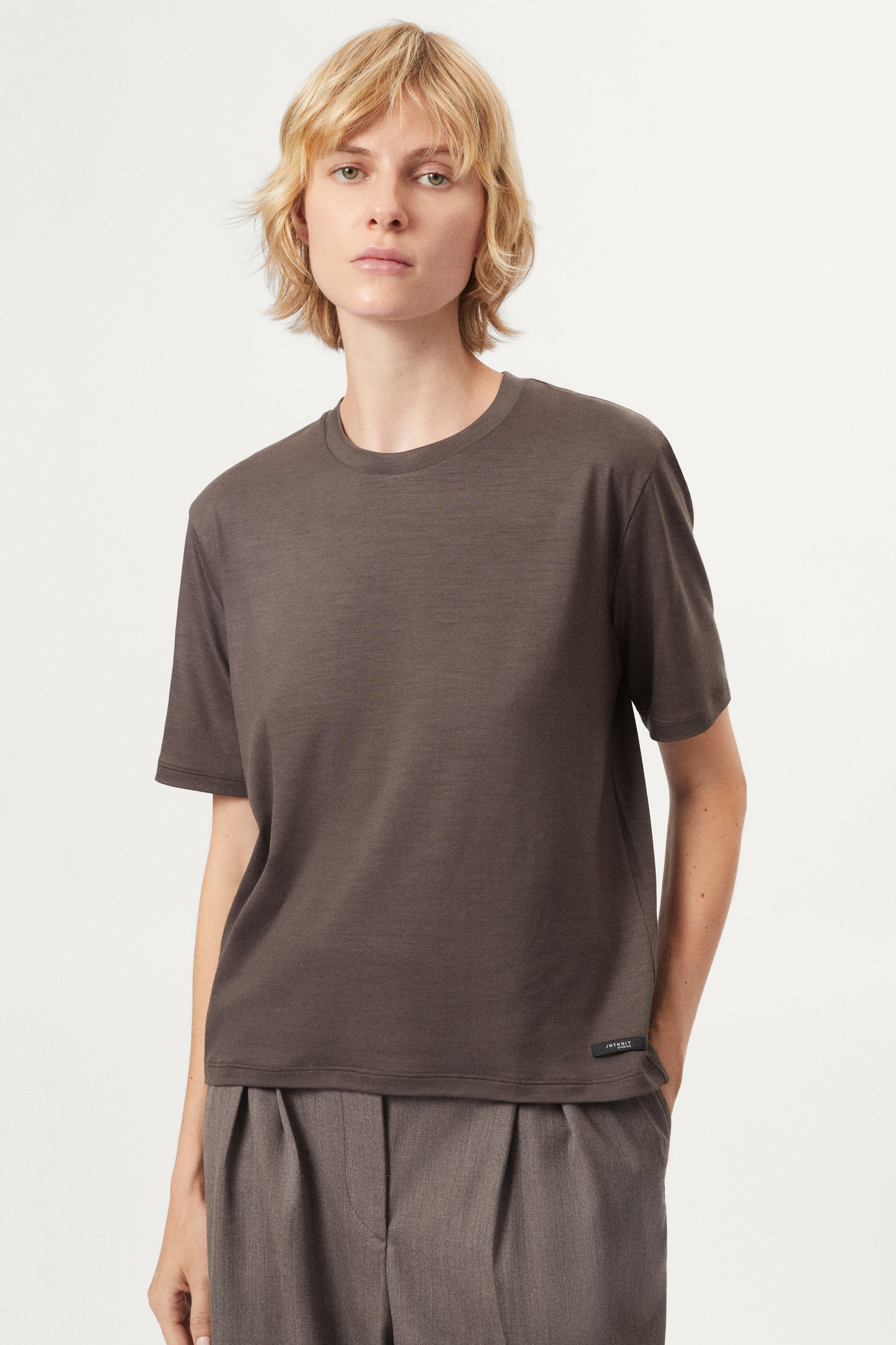 Person wearing a brown t-shirt and pants on a white background