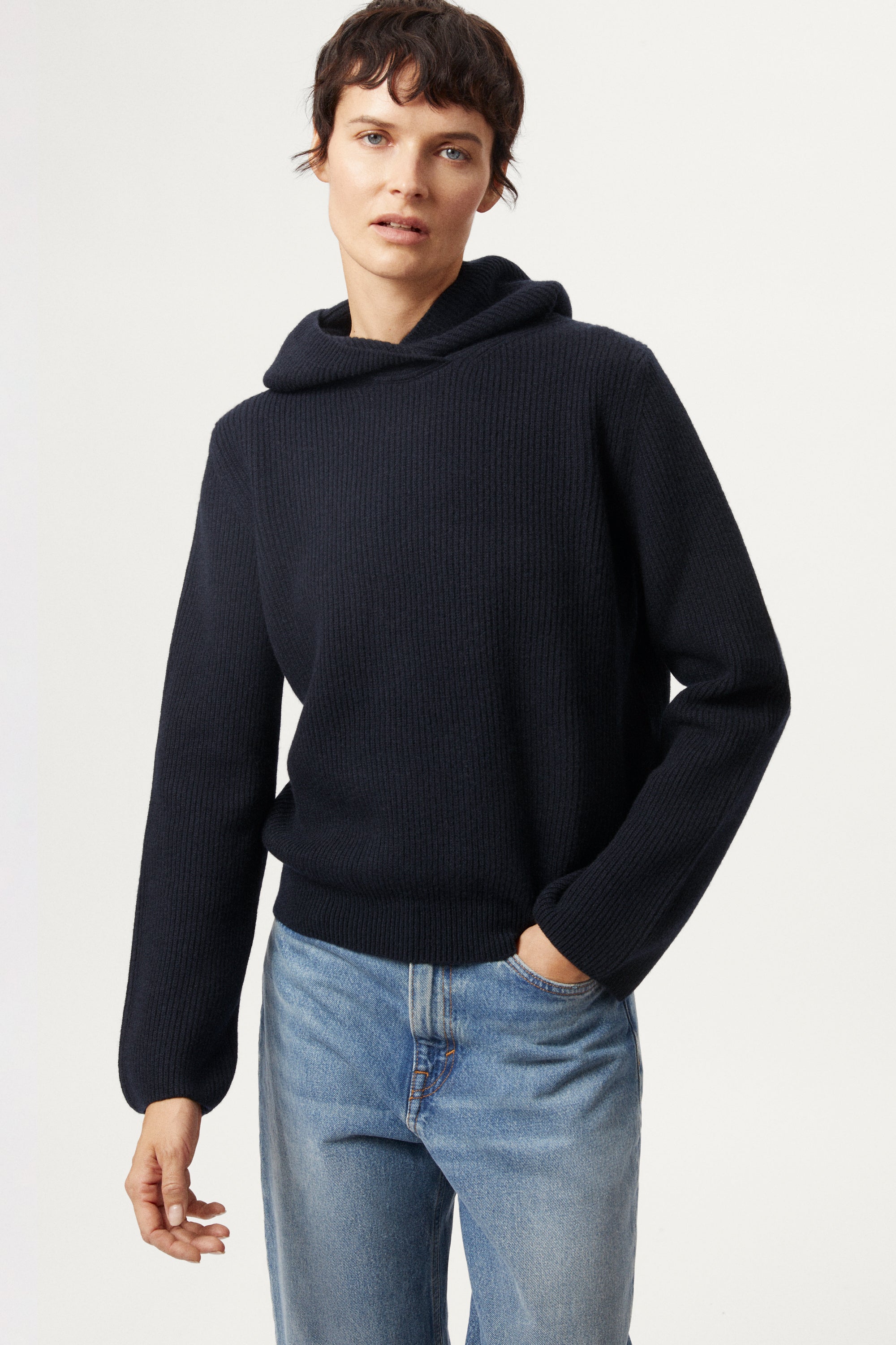 Person wearing a blue navy Woolen Ribbed Hoodie and blue jeans on a white background