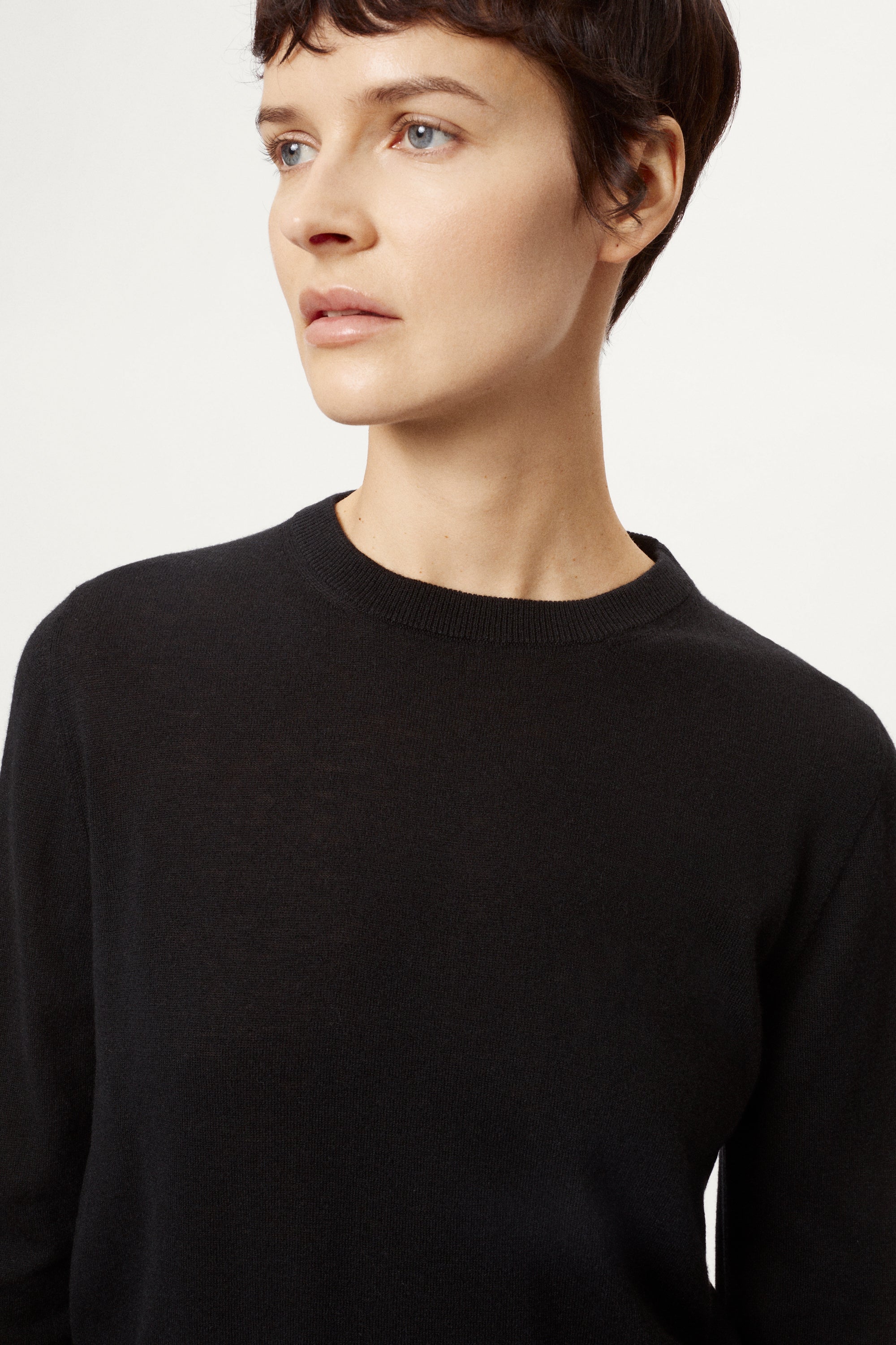 Person wearing a black sweater and black pants on a white background