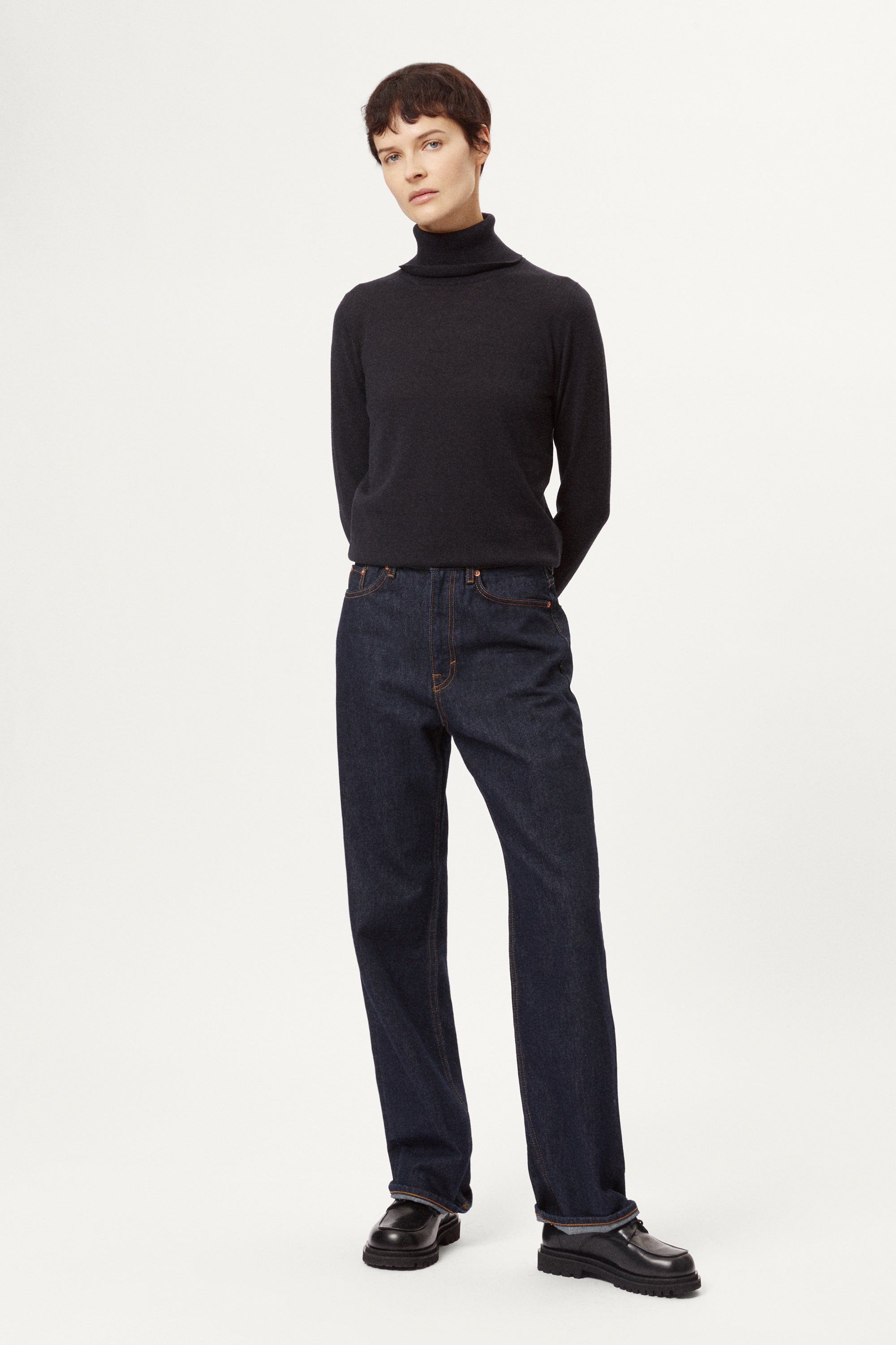 Person wearing a blue turtleneck sweater against a white background