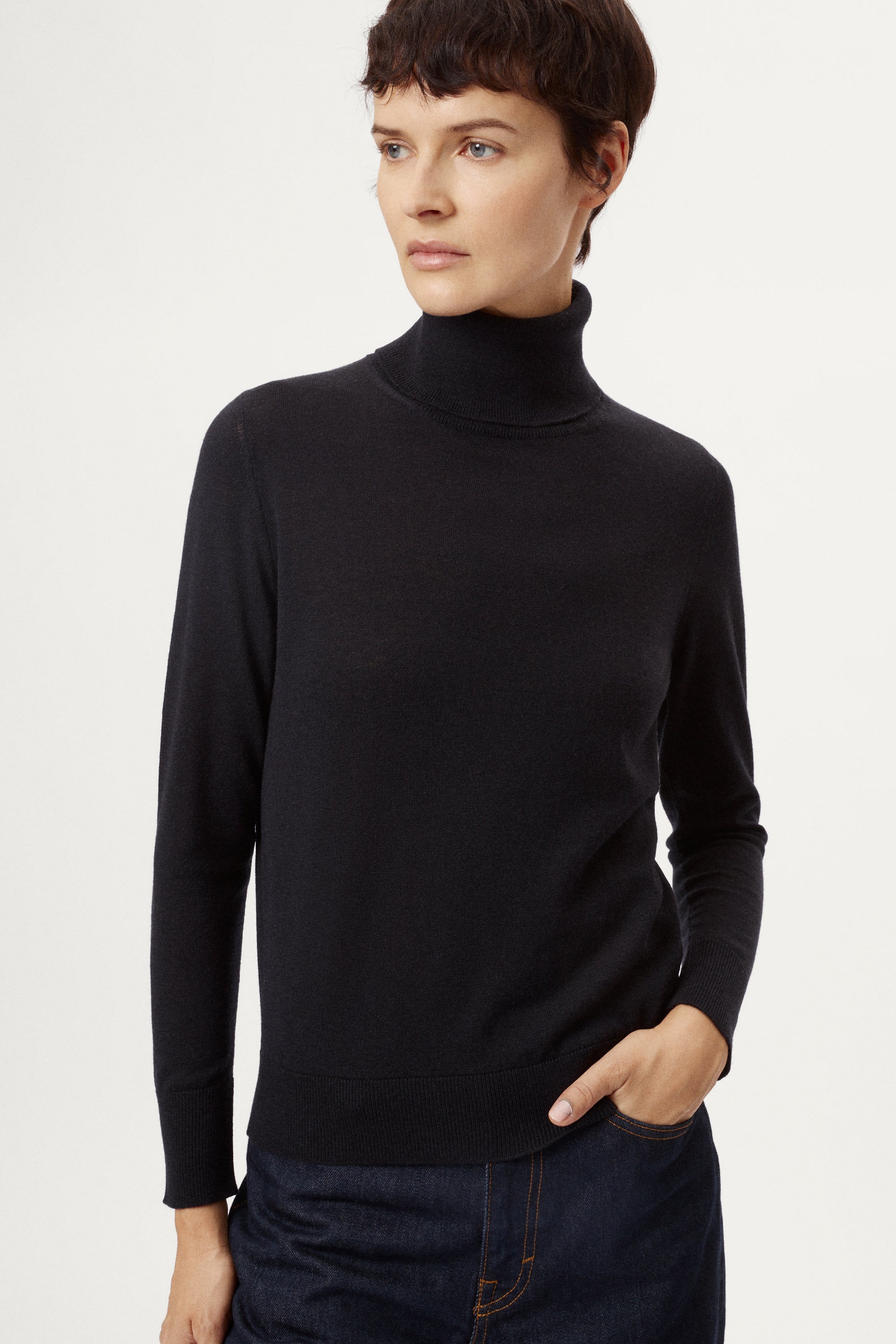 Person wearing a blue turtleneck sweater against a white background