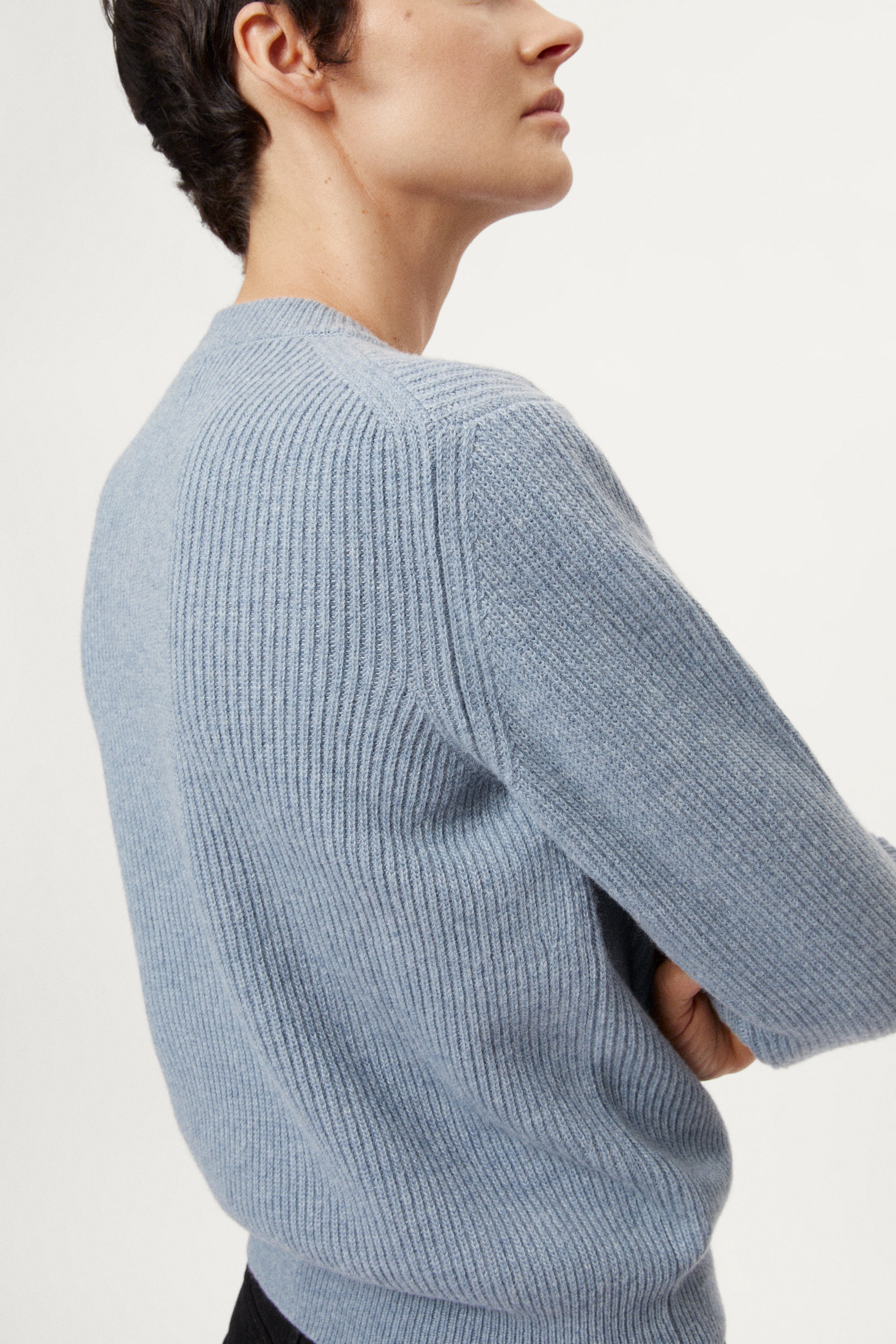 Woman wearing a wool light blue sweater on a white background