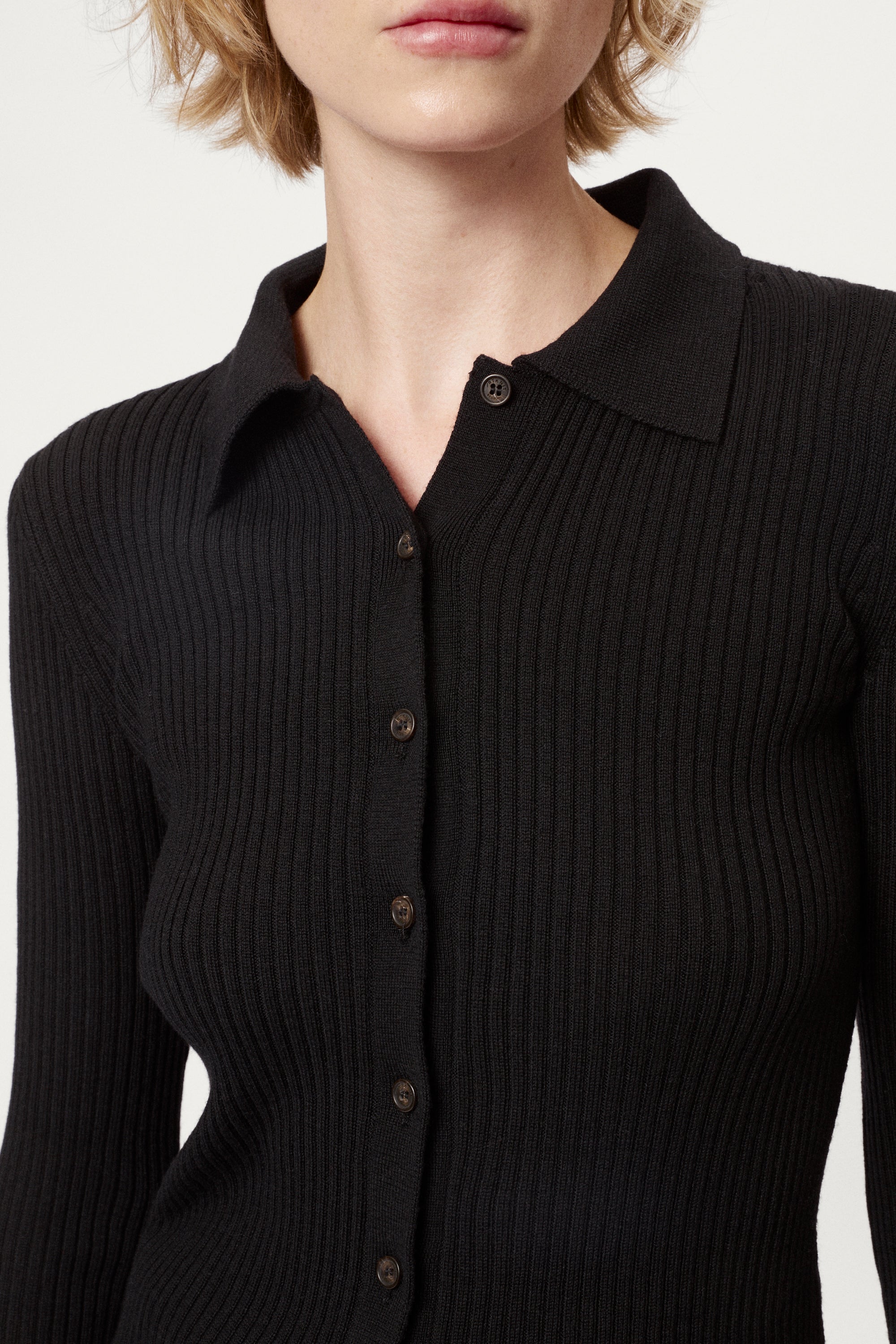 Woman wearing a black ribbed merino shirt  on a white background