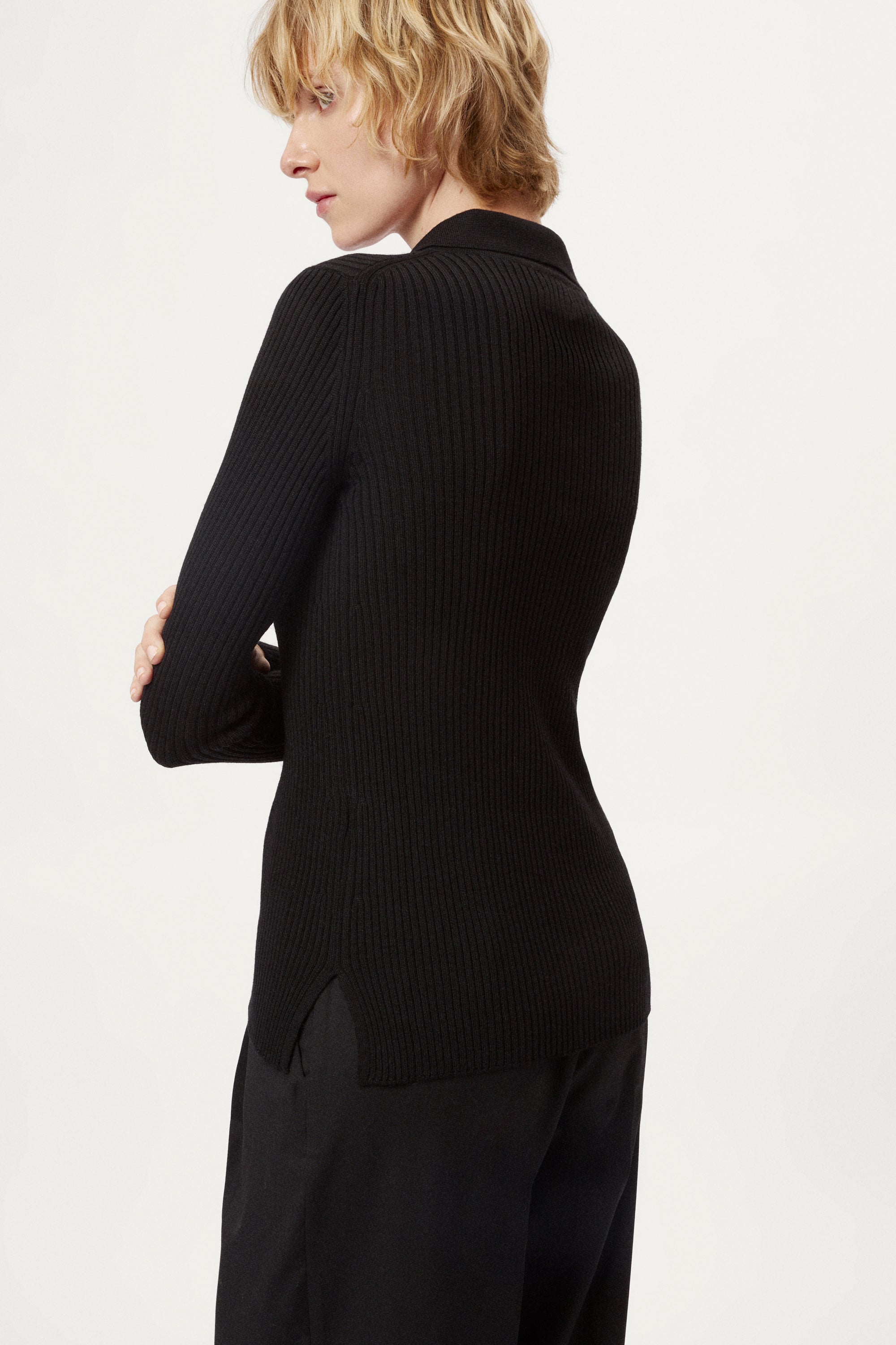 Woman wearing a black ribbed merino shirt  on a white background