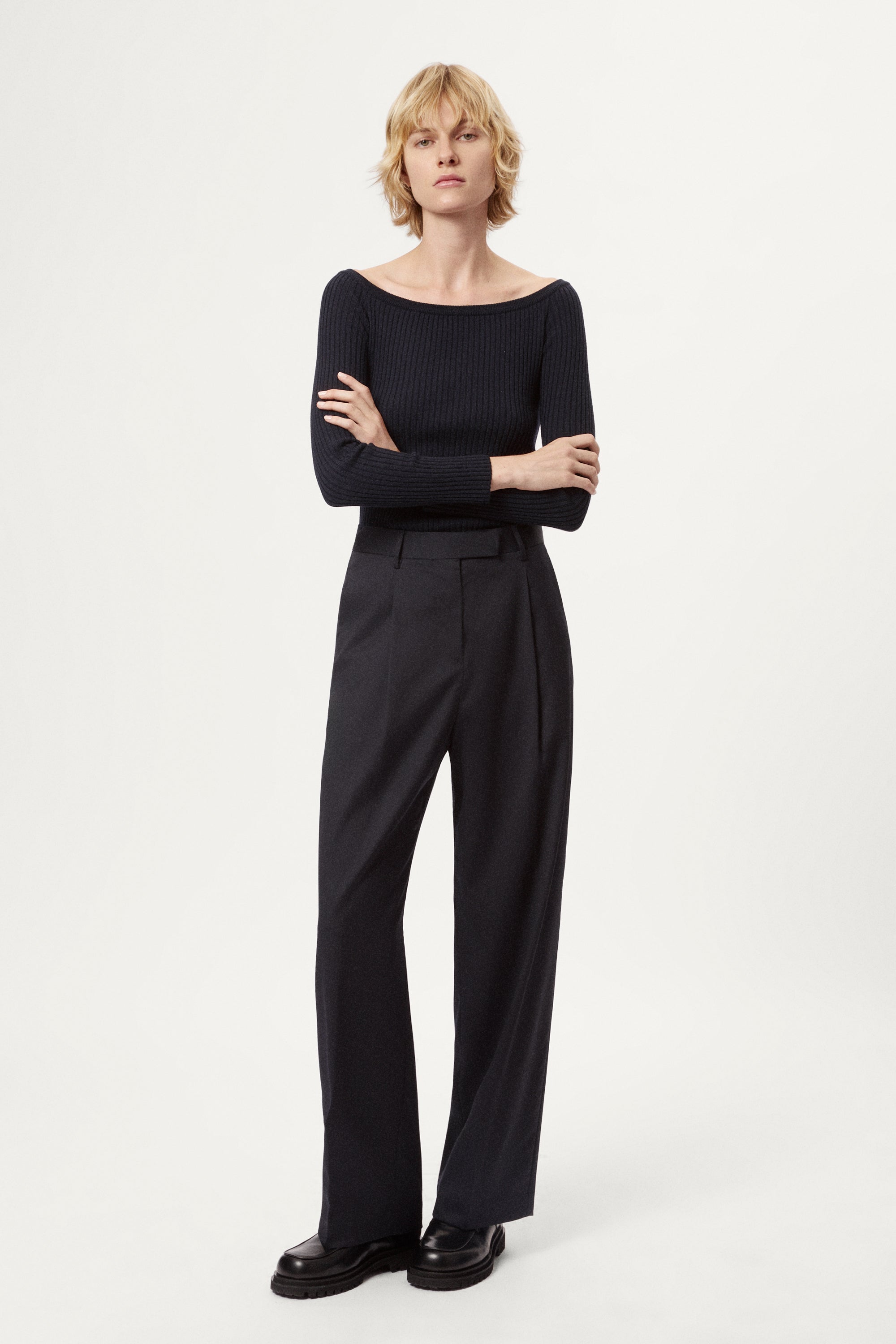 Woman wearing a blue off-shoulder sweater and black skirt on a white background