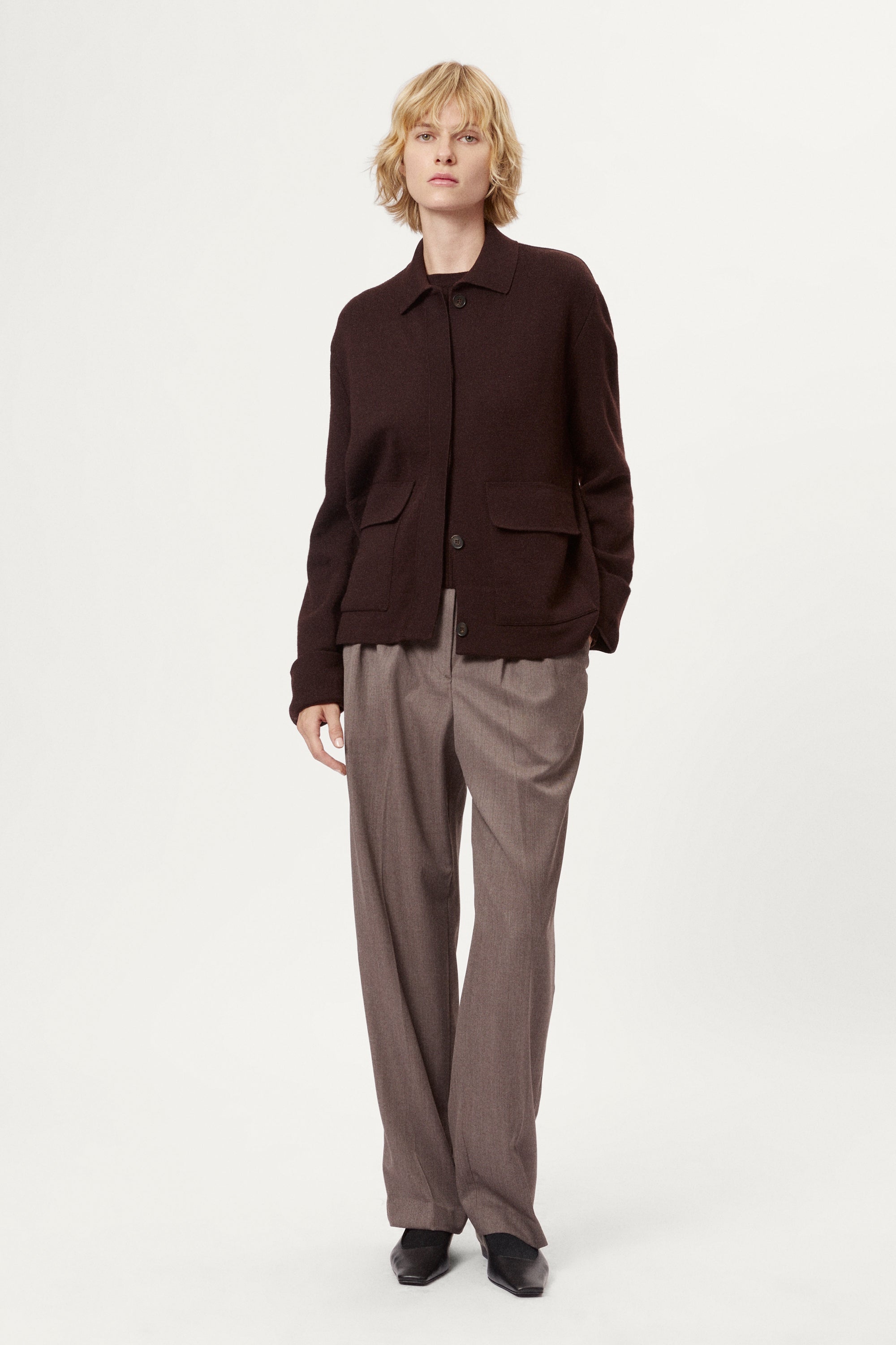 Woman wearing a dark brown jacket and pants on a white background