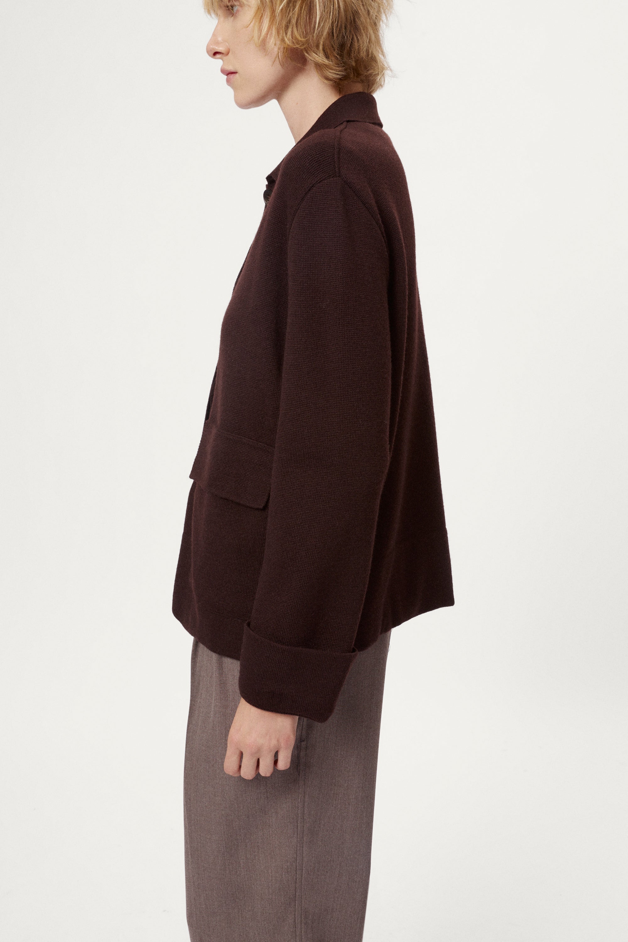 Woman wearing a dark brown jacket and pants on a white background