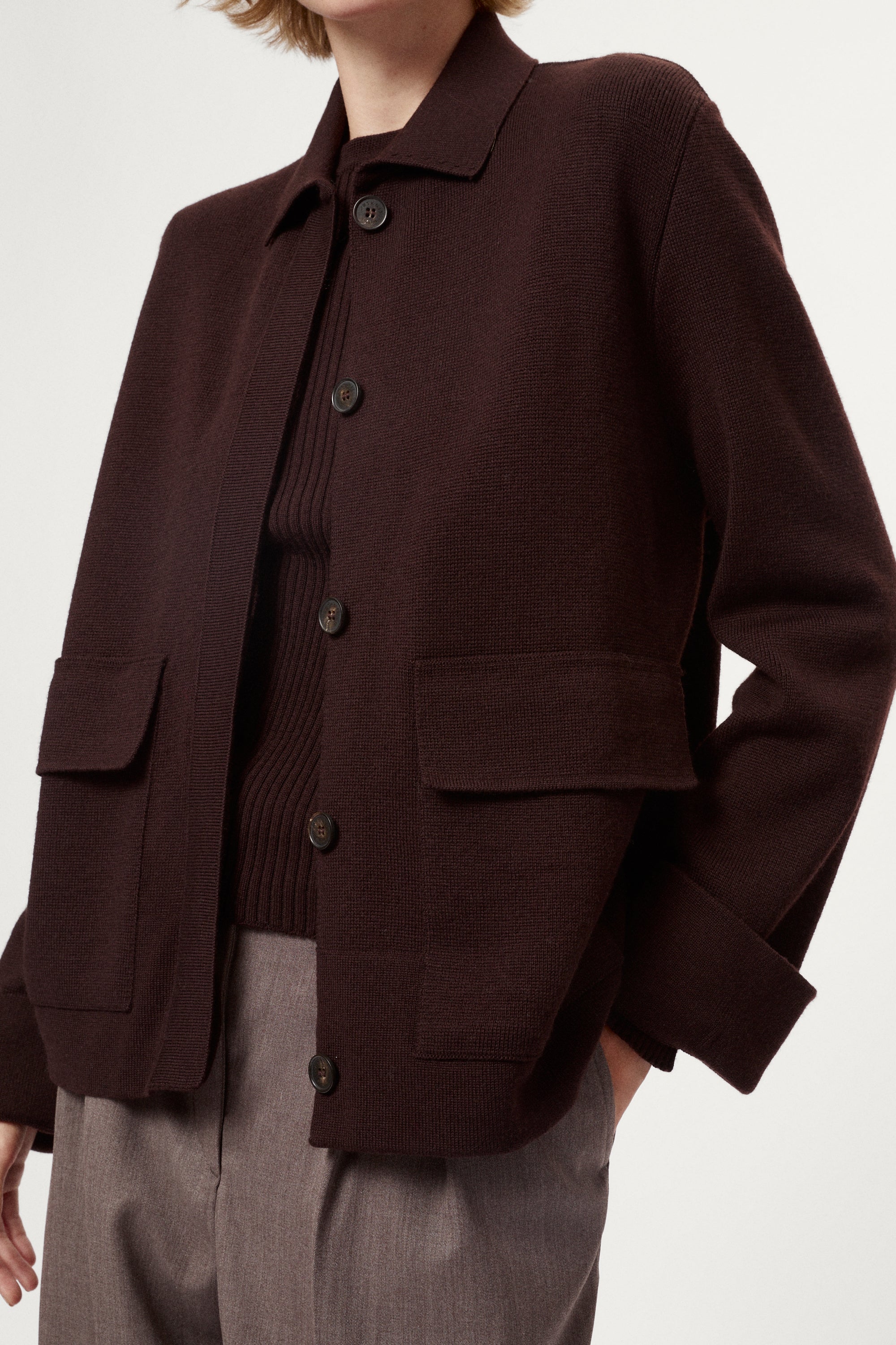 Woman wearing a dark brown jacket and pants on a white background