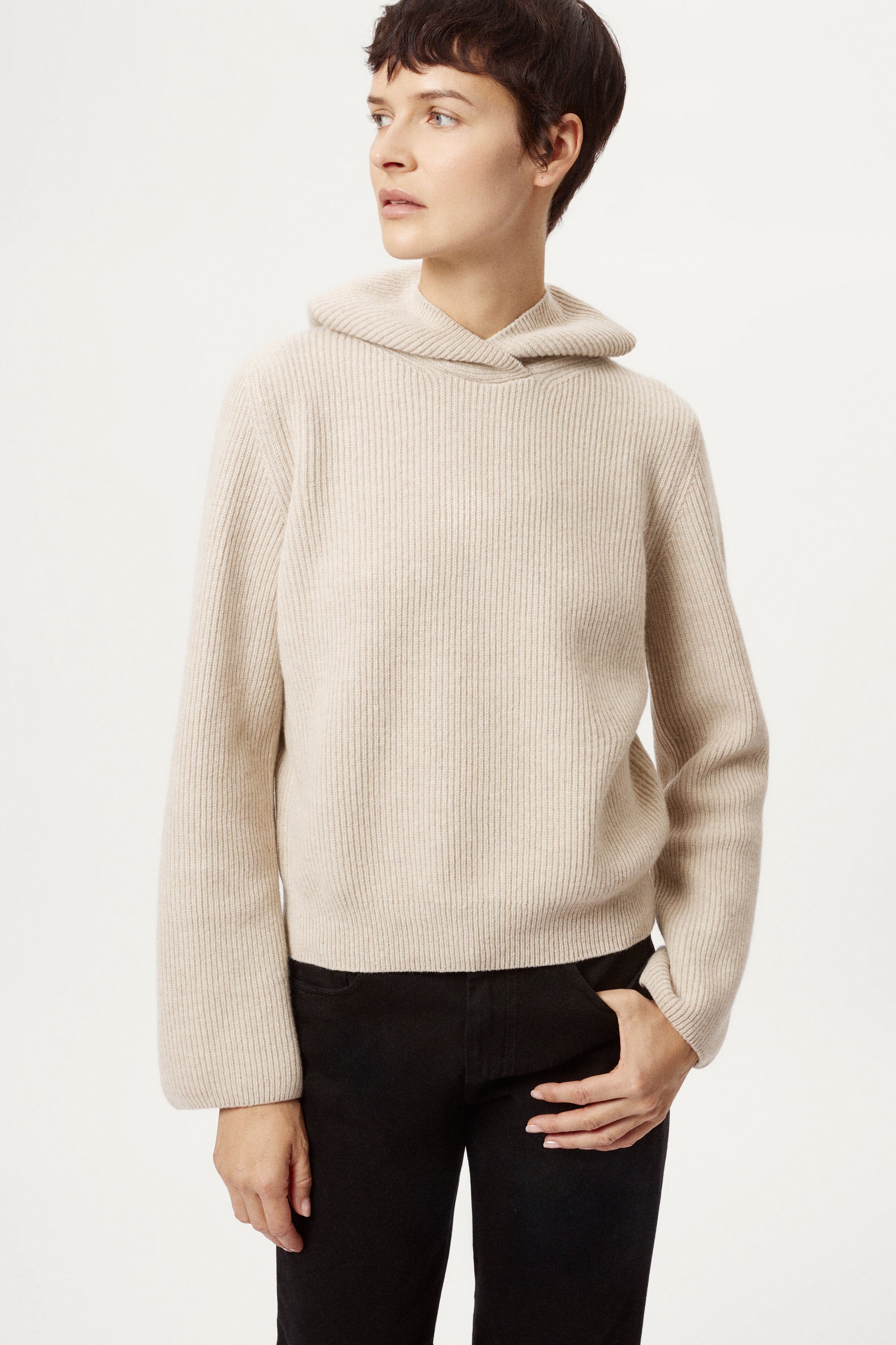 Woman wearing a beige sweater against a plain background