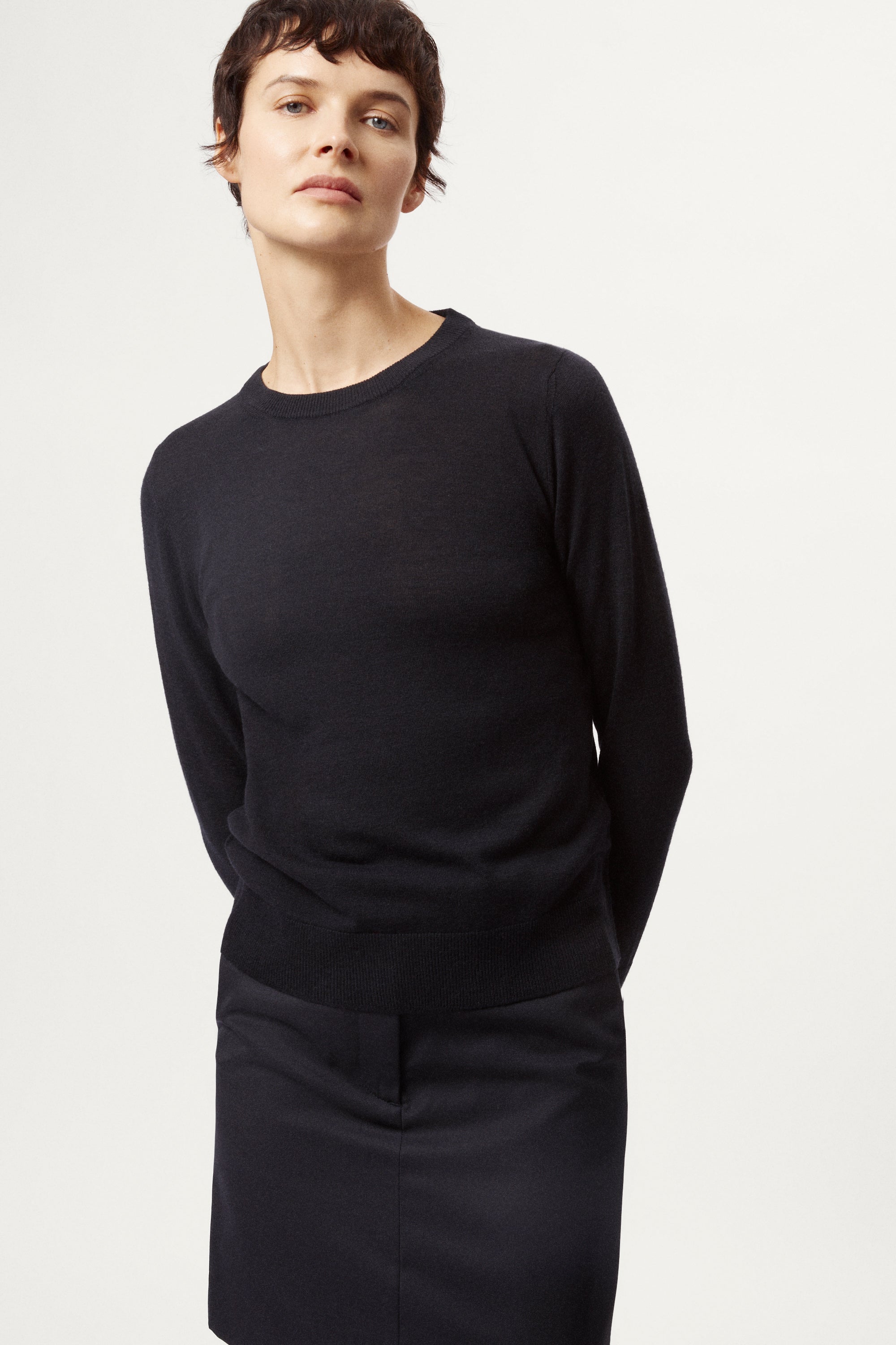 Person wearing a blackwool long-sleeve sweater and skirt 