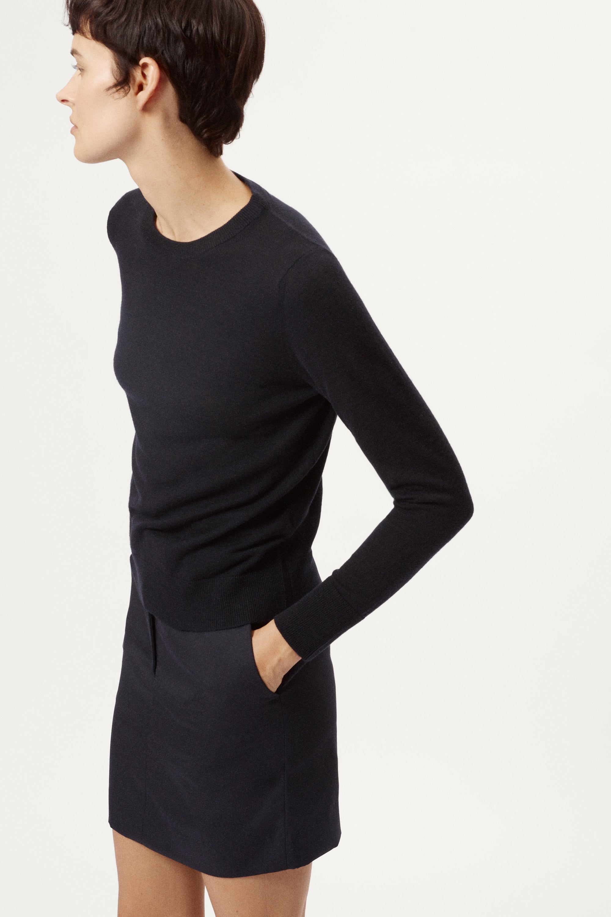 Person wearing a black long-sleeve top and skirt set on a white background