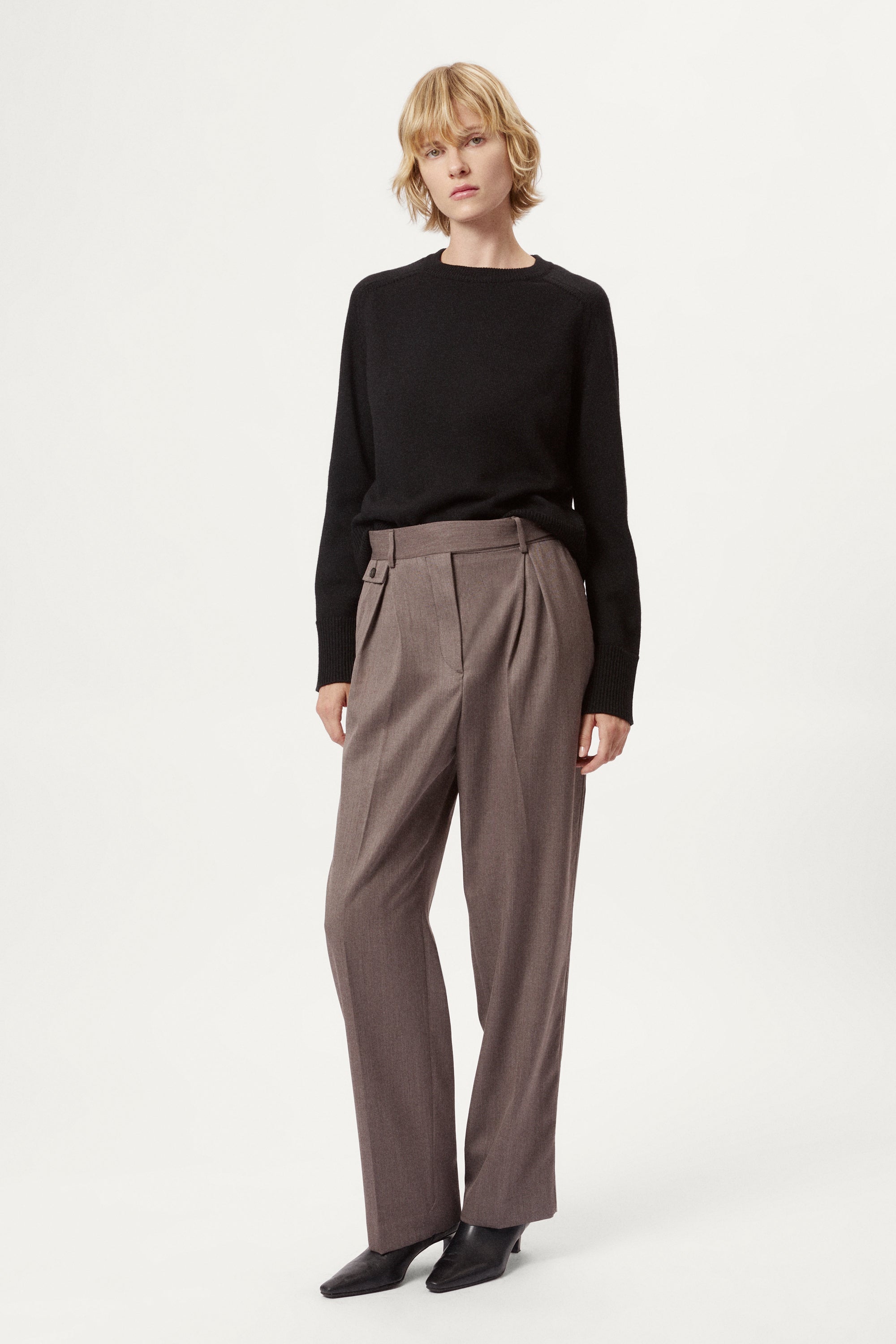 Woman wearing a black merino  sweater on a plain background