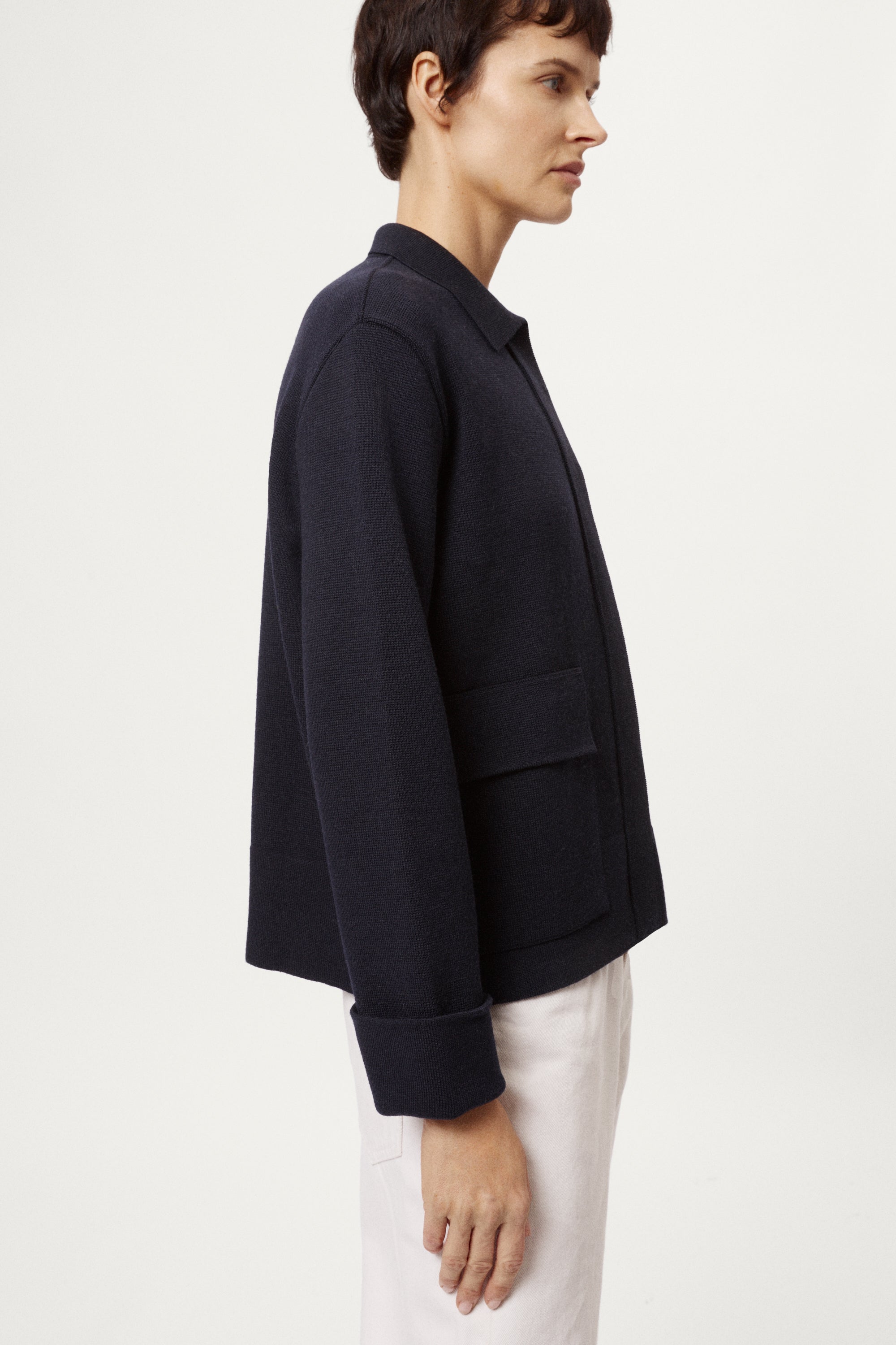 Woman wearing a blue jacket and white pants on a white background