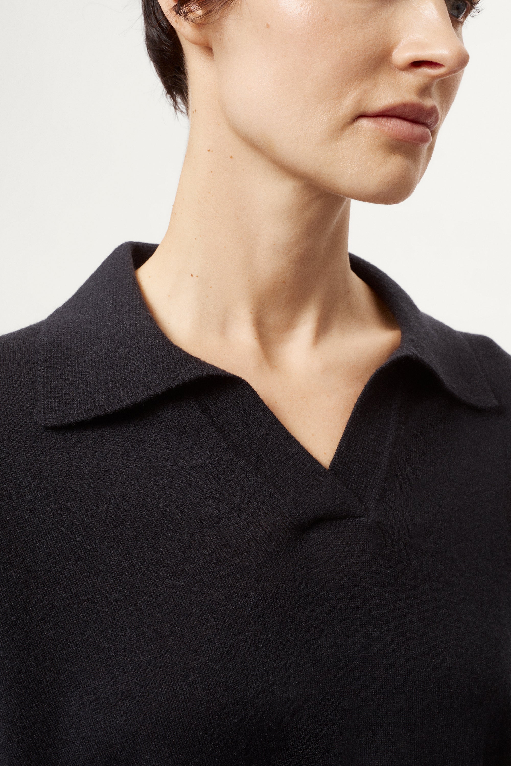 Close-up of a person wearing a blue polo shirt with a collar against a neutral background