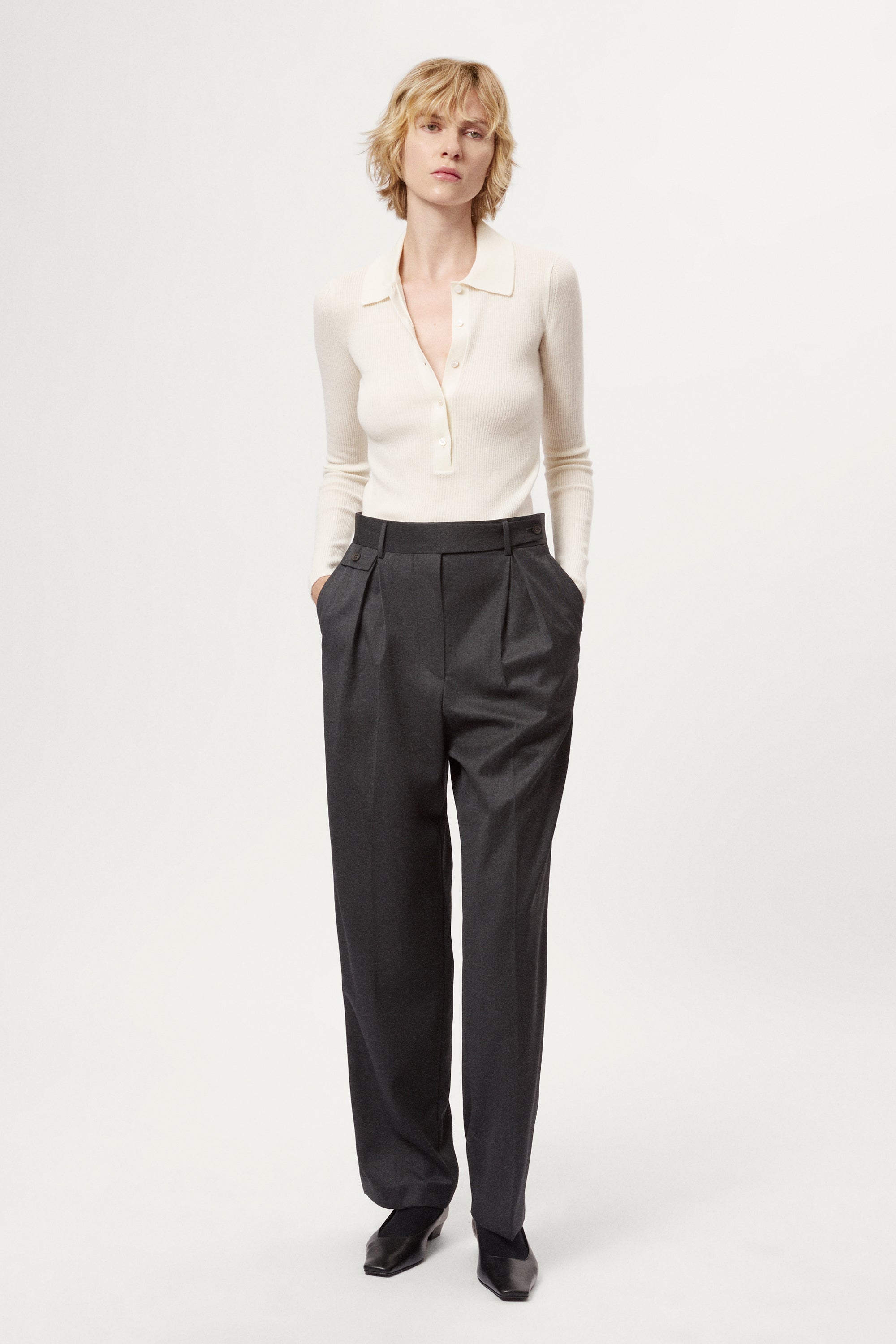 Person wearing a white merino shirt and dark gray pants on a white background