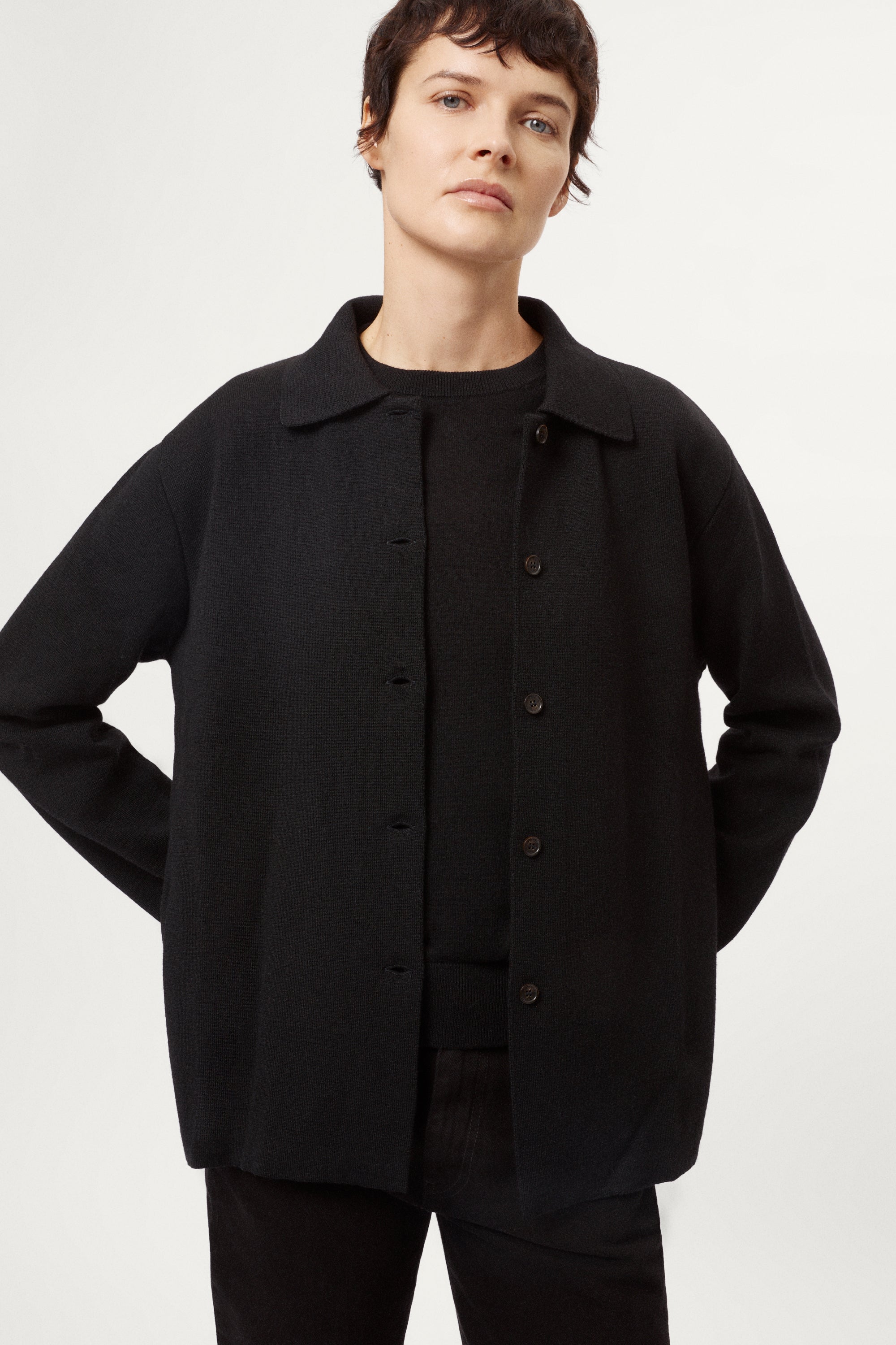 Person wearing a black merino wool jacket on a white background