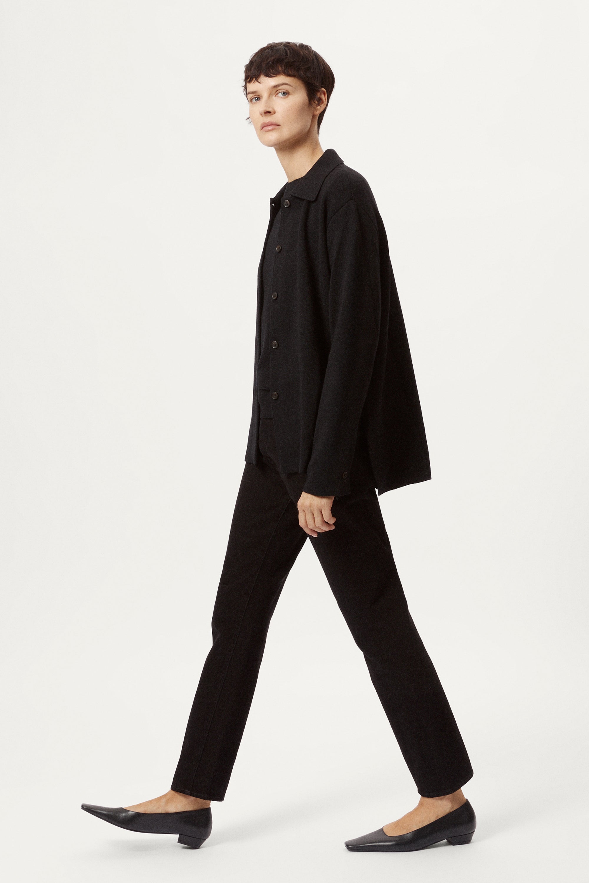 Person wearing a black merino wool jacket on a white background