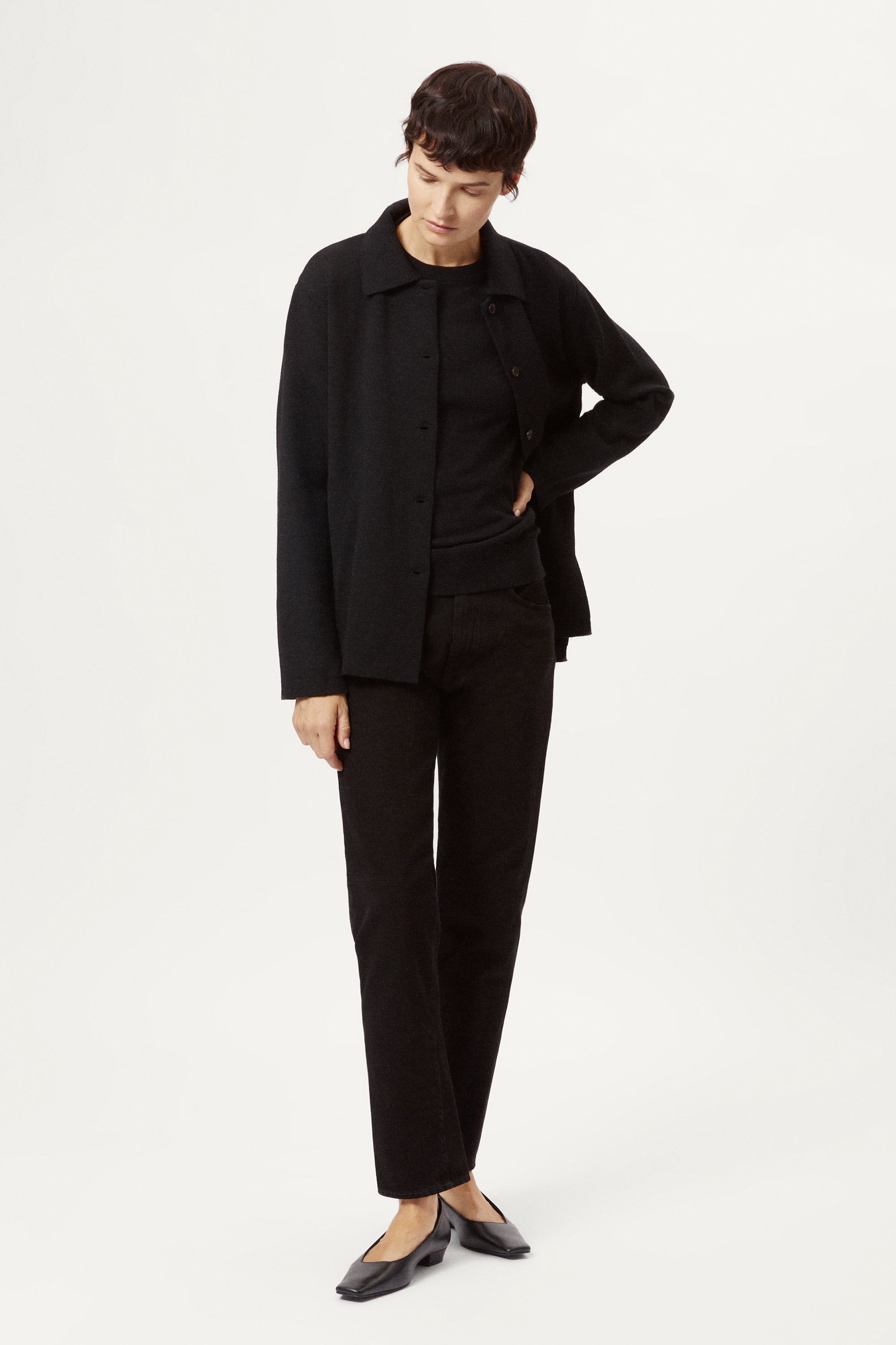 Person wearing a black merino wool jacket on a white background