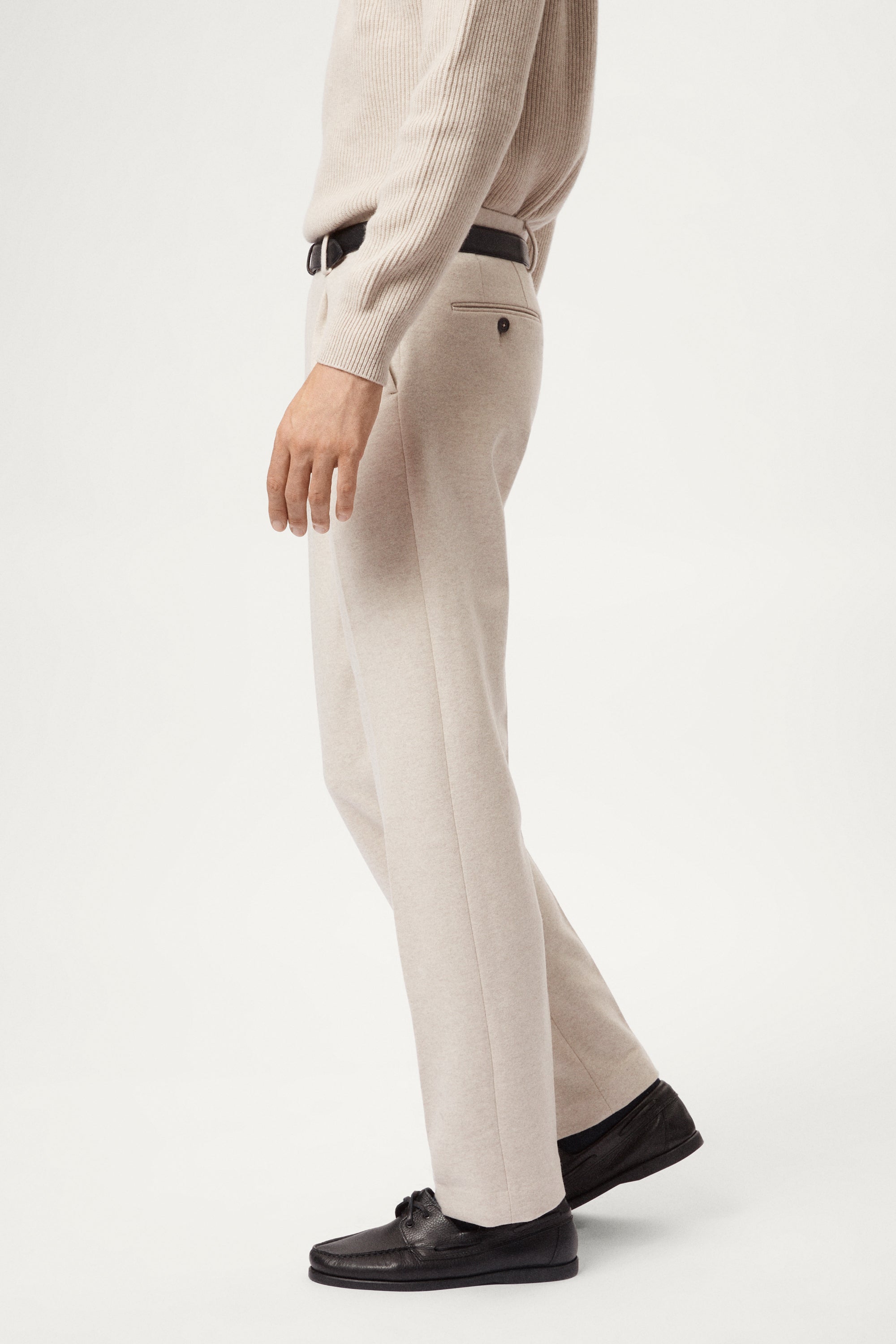 Person wearing a woolen beige pants and a light sweater on a white background