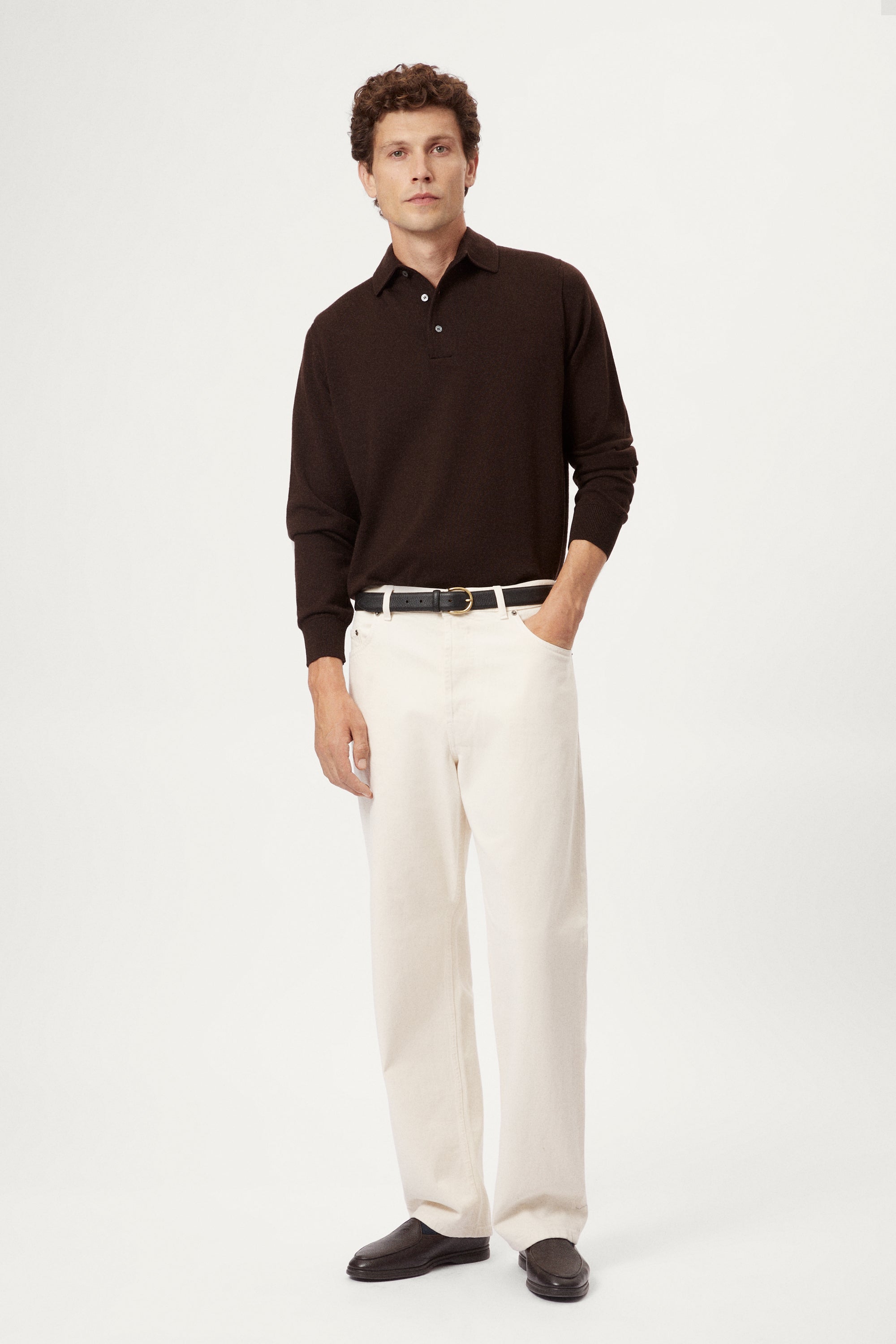 Man wearing a brown long-sleeve shirt and white pants on a white background