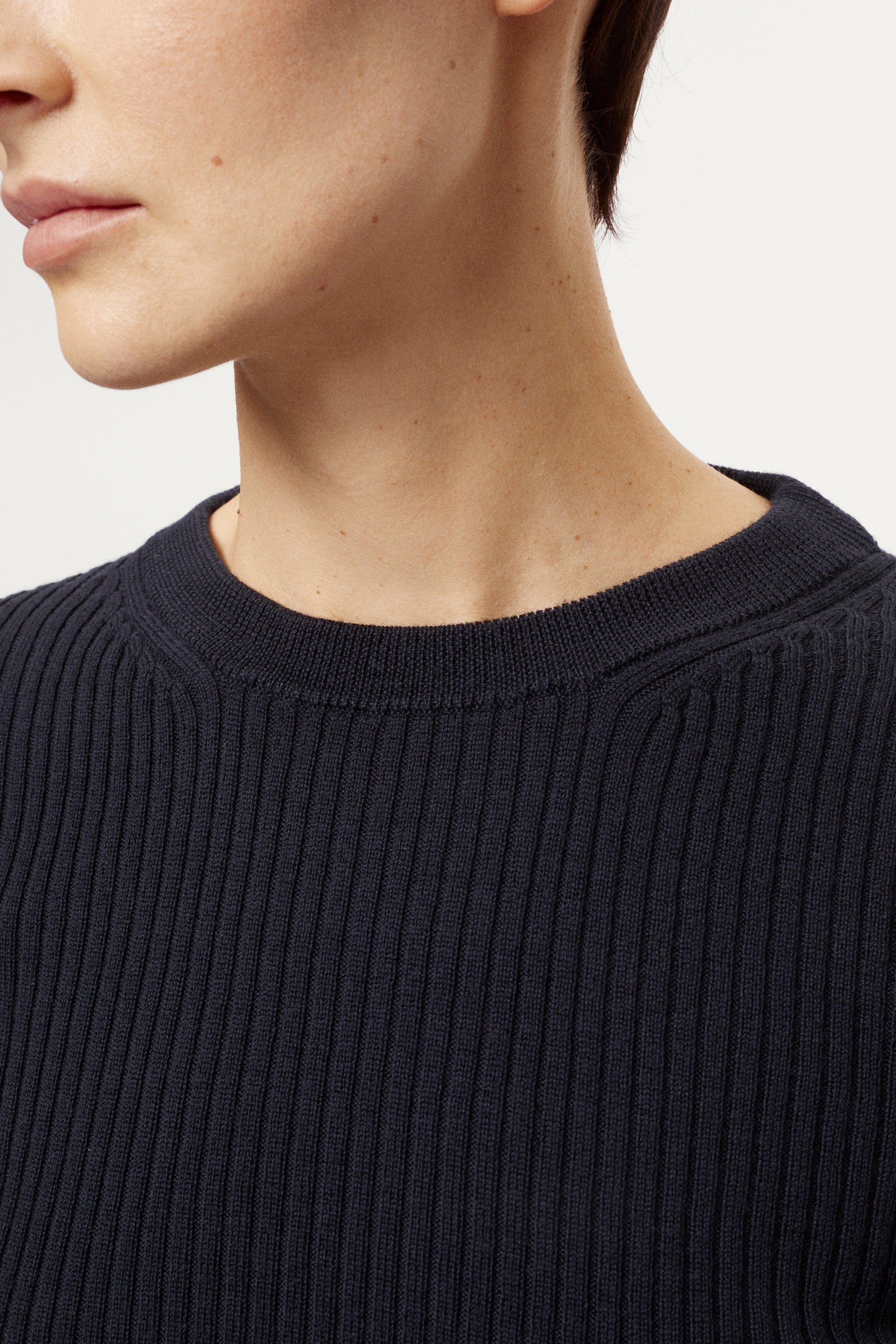 Woman wearing a blue sweater and light blue jeans on a white background