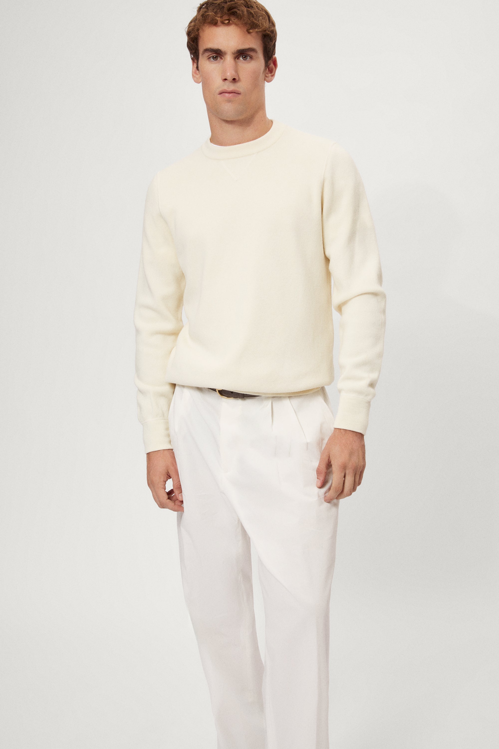 Man wearing a white Merino Wool Sweatshirt and white pants on a plain background