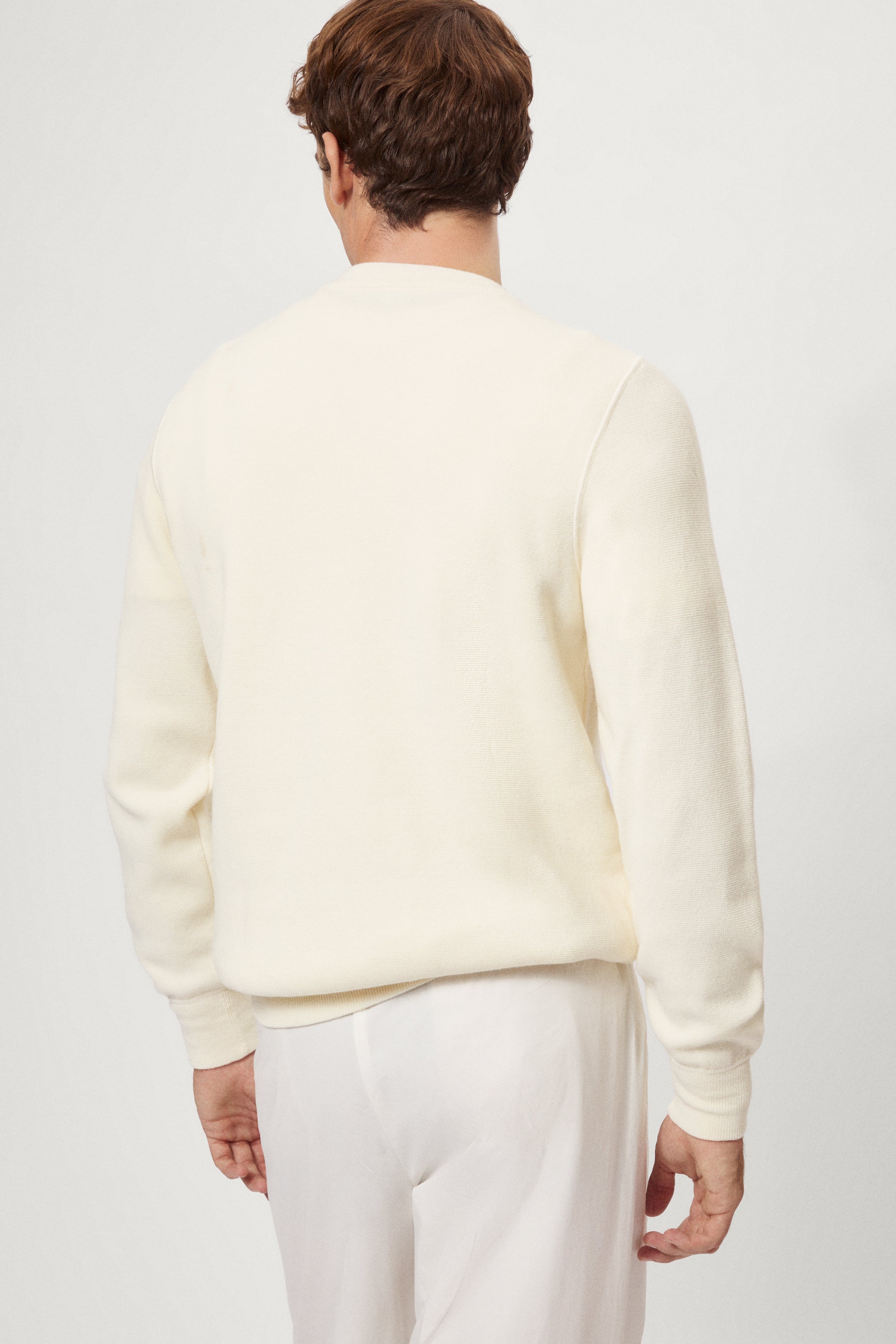 Man wearing a white Merino Wool Sweatshirt and white pants on a plain background