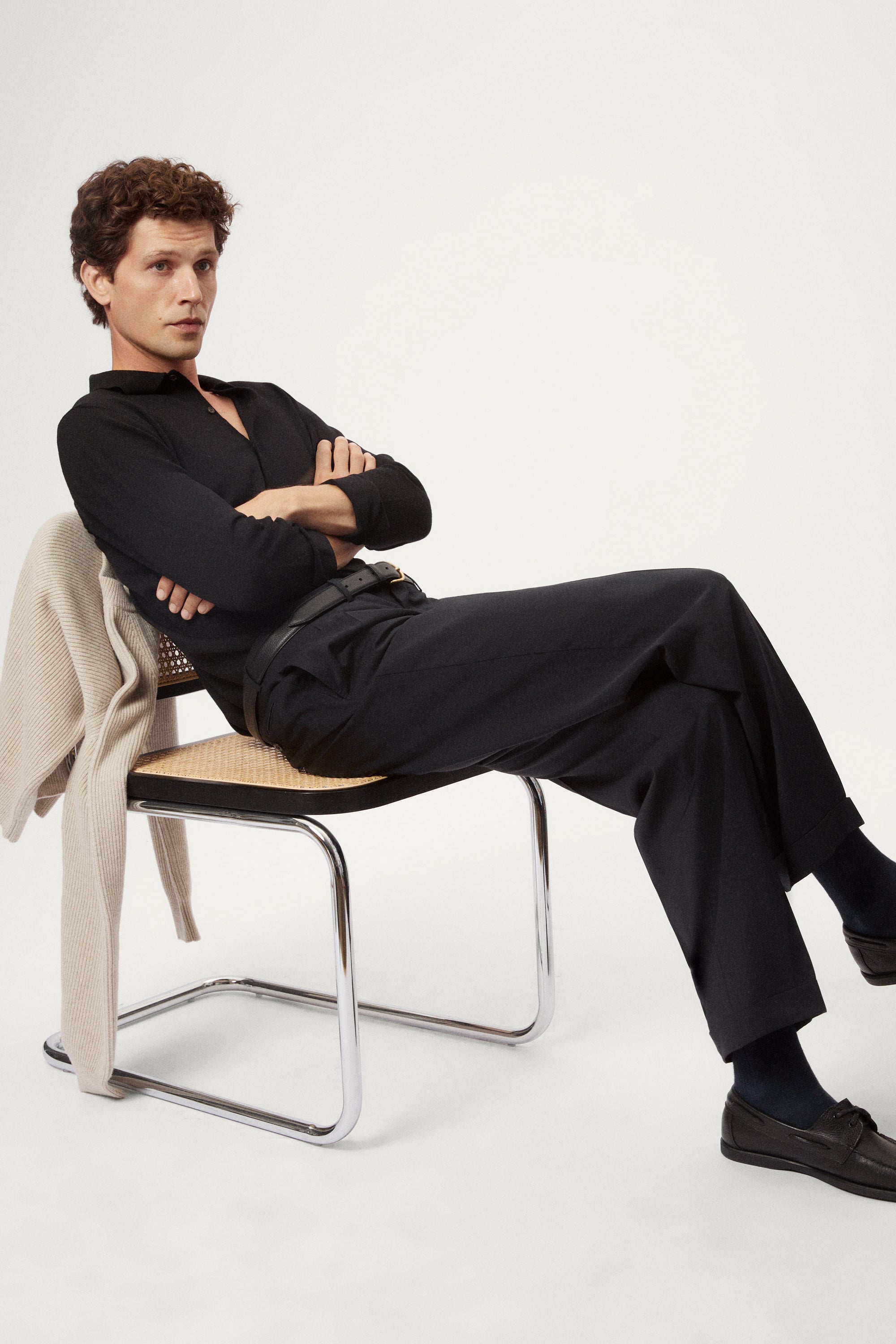 Man wearing a black shirt and grey pants on a white background