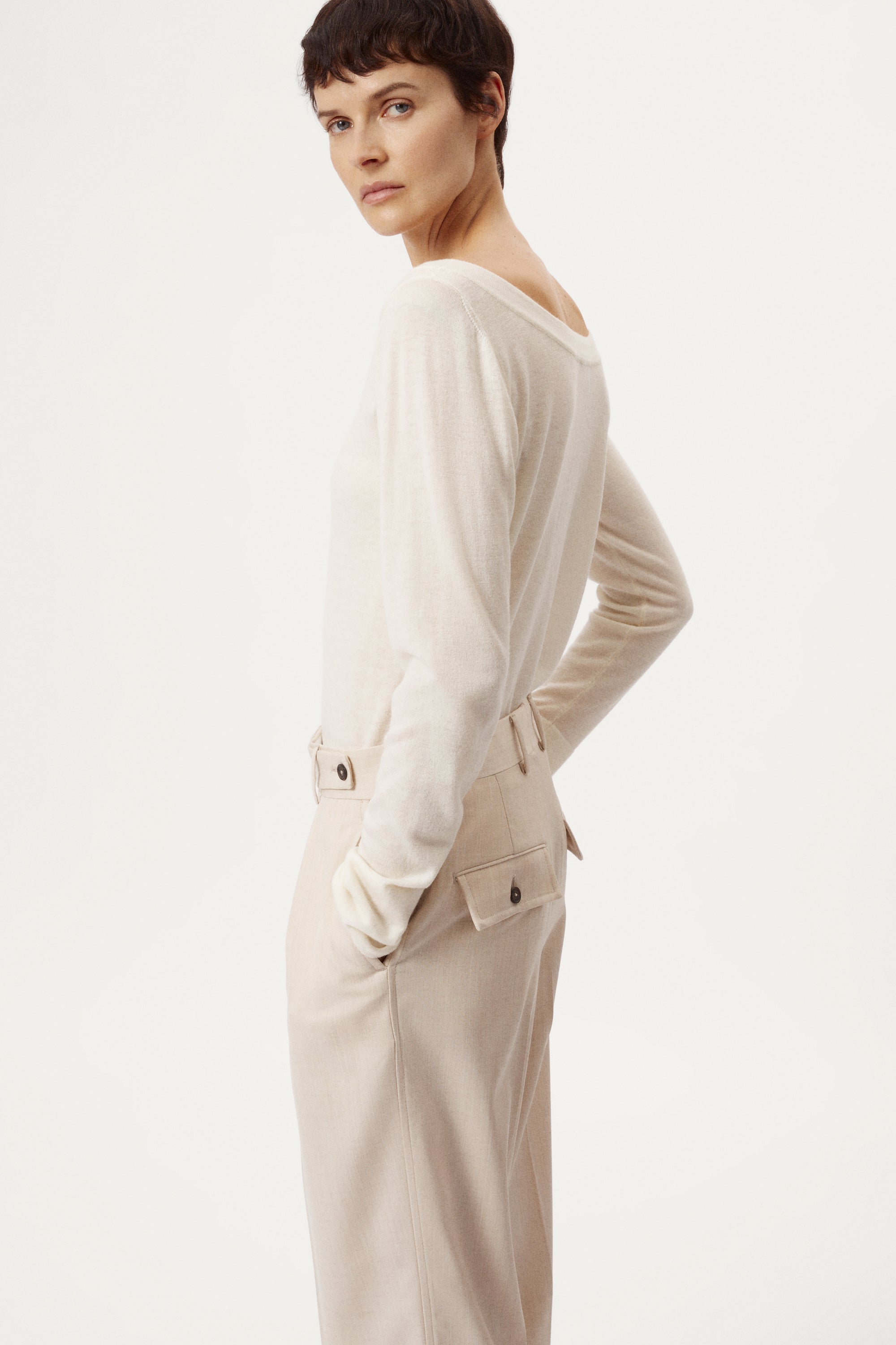 Person wearing a white sweater and black pants on a white background