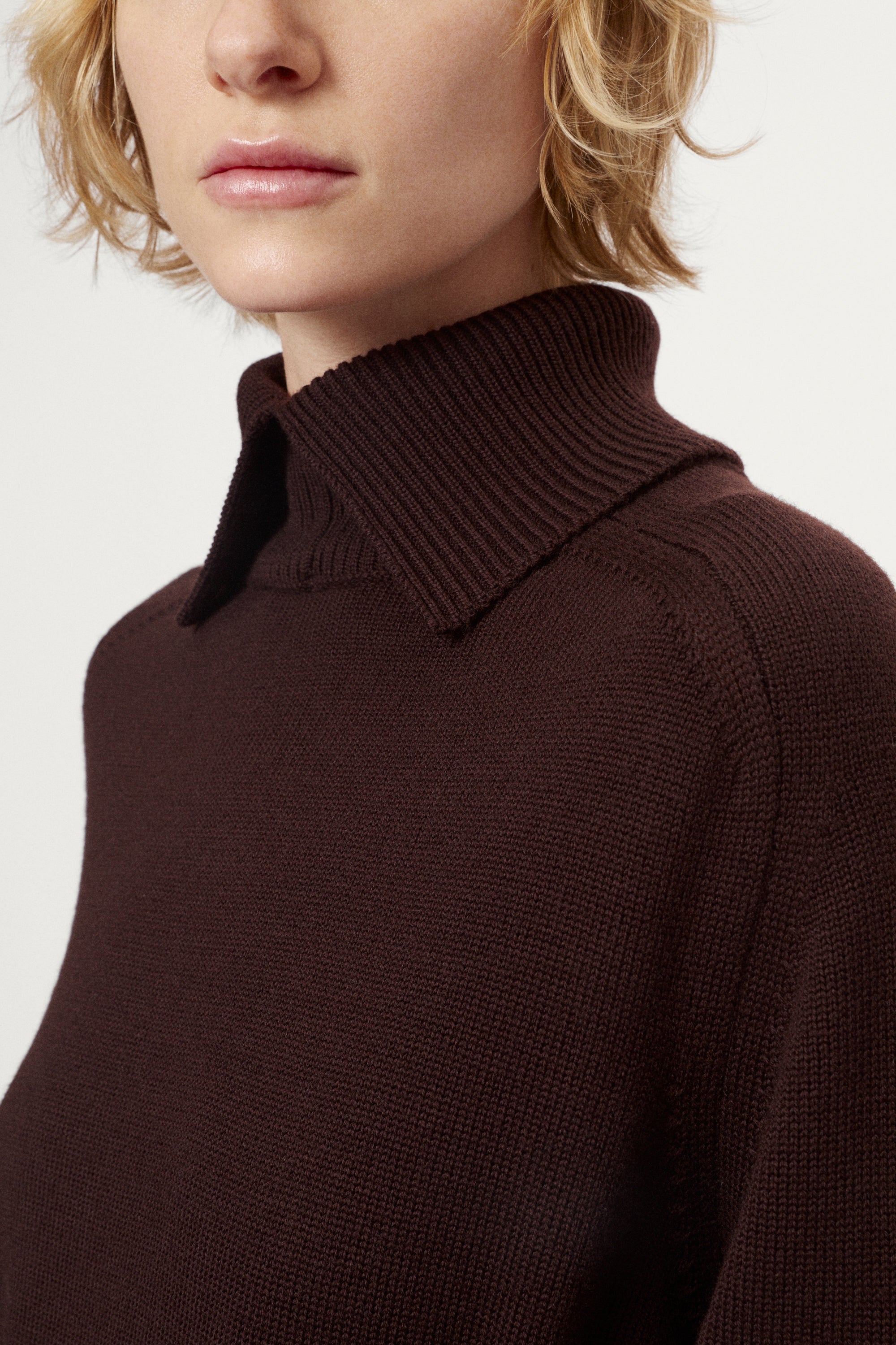 Close-up of a person wearing a brown turtleneck sweater on a white background