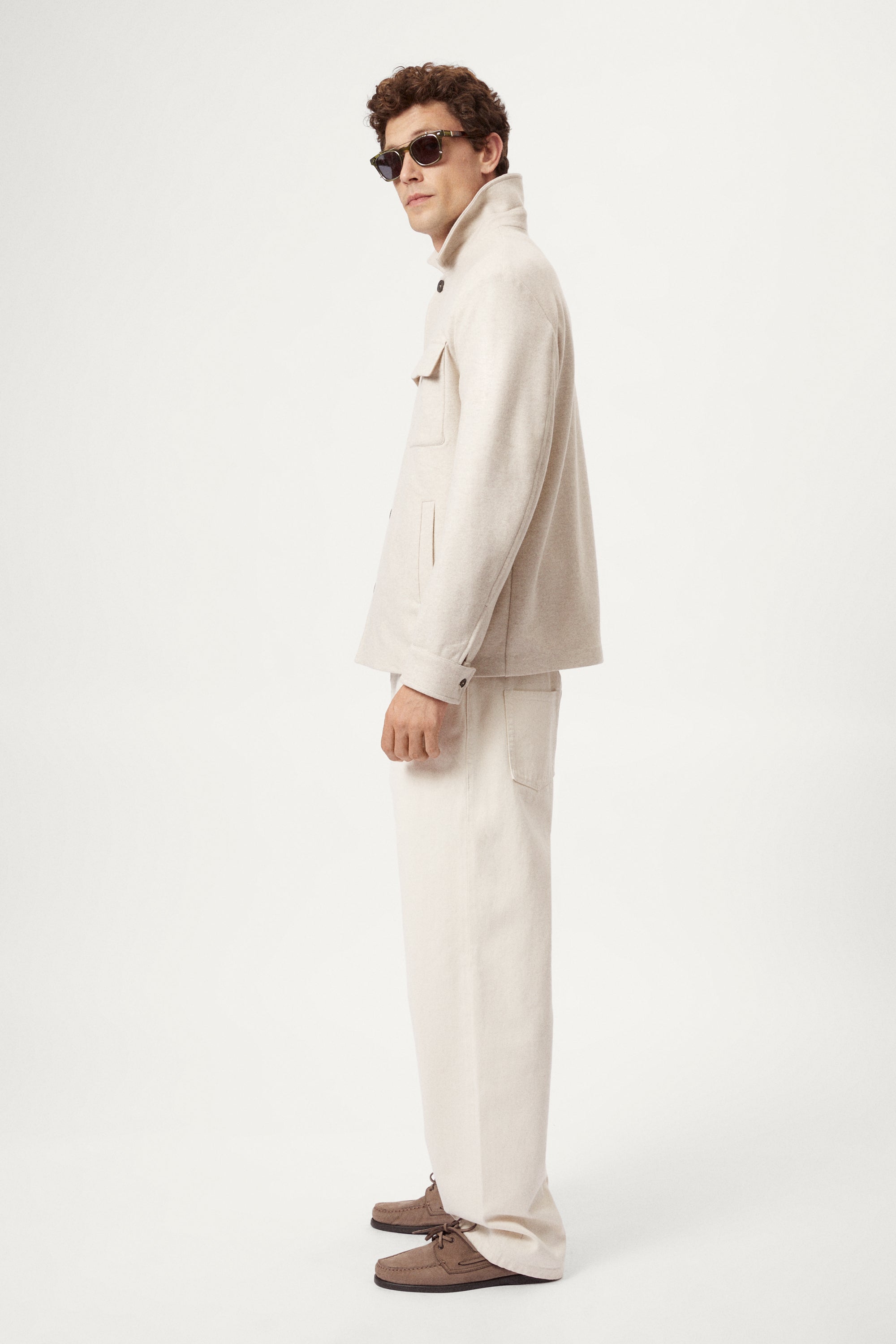 Man wearing a woolen ecru jacket with button details on a white background