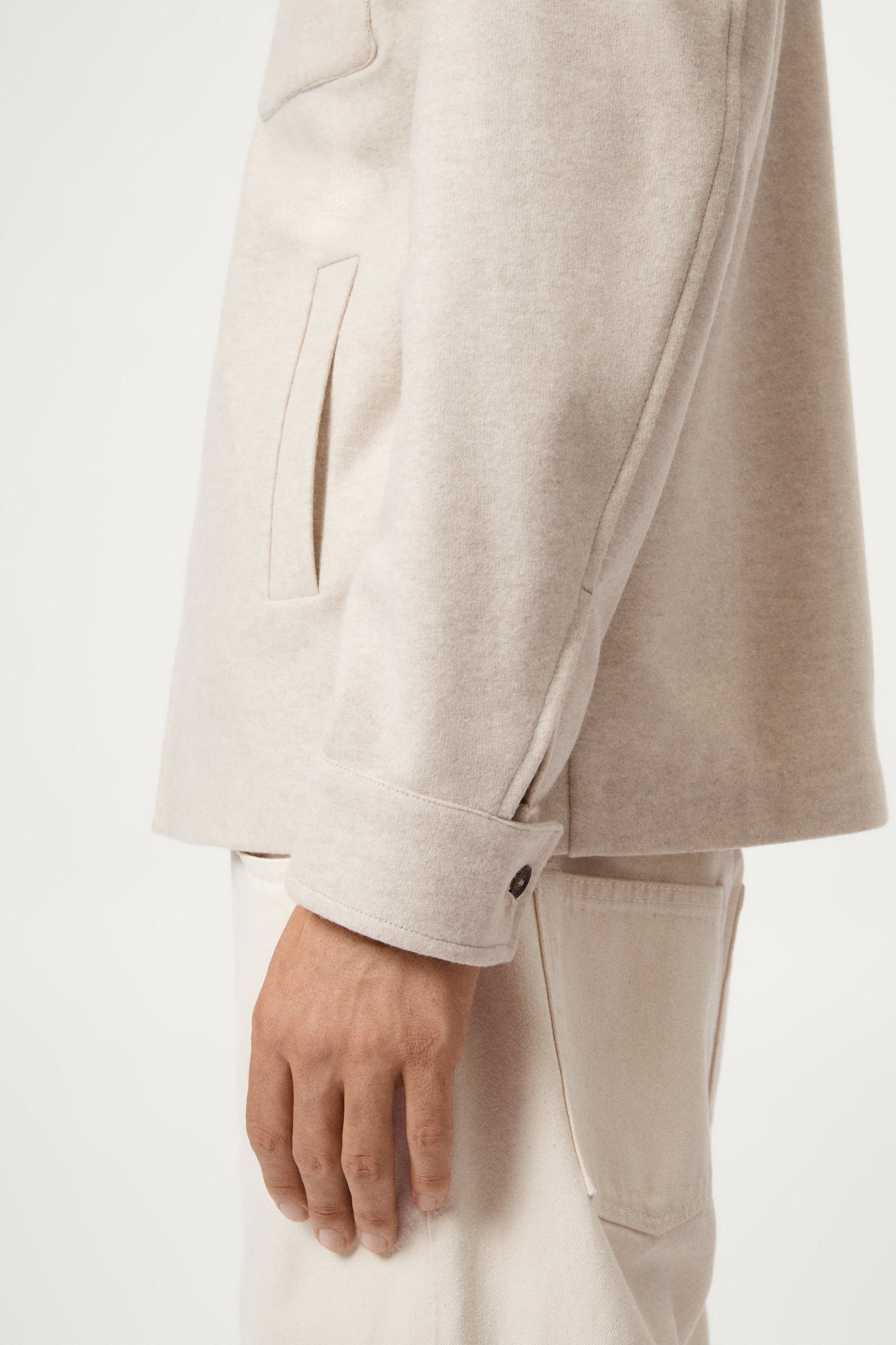 Man wearing a woolen ecru jacket with button details on a white background