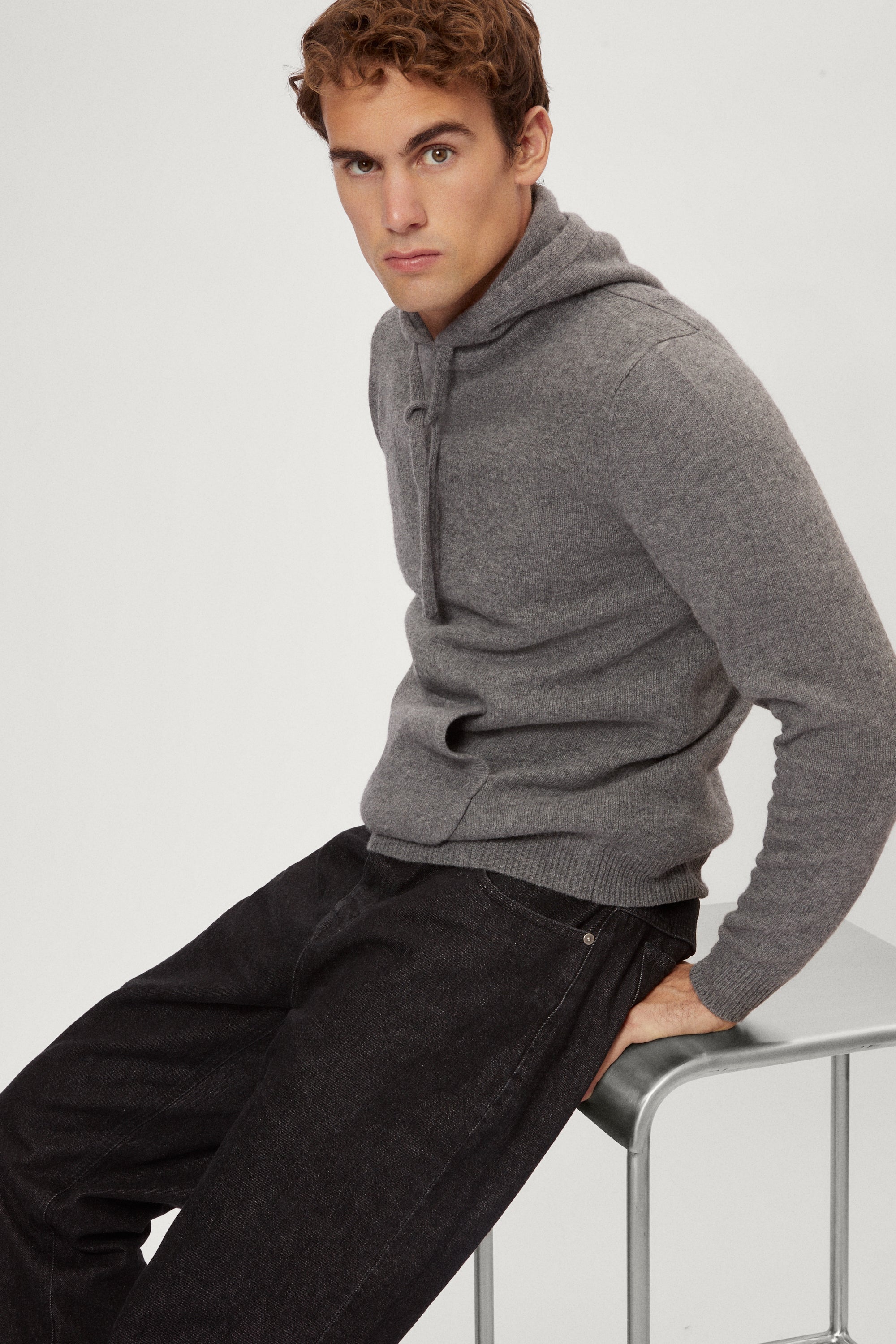 Man wearing a light gray woolen  hoodie on a white background