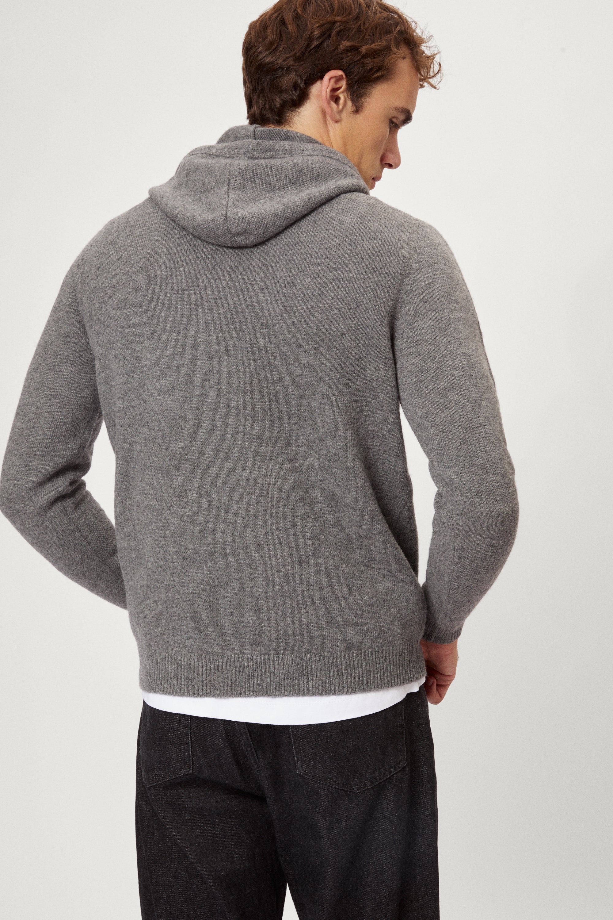 Man wearing a light gray woolen  hoodie on a white background