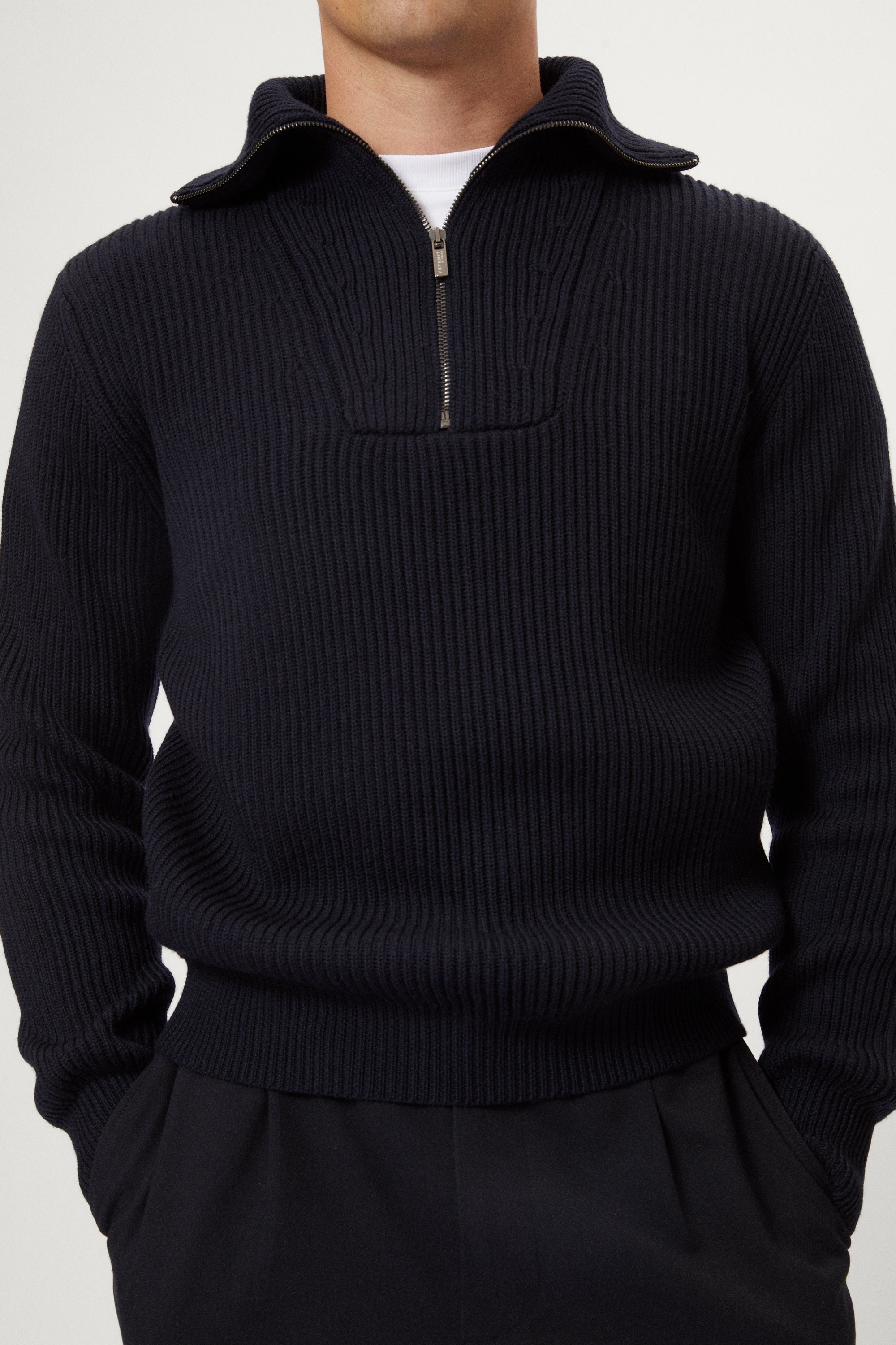 Man wearing a dark blue merino half zip sweater with a white background
