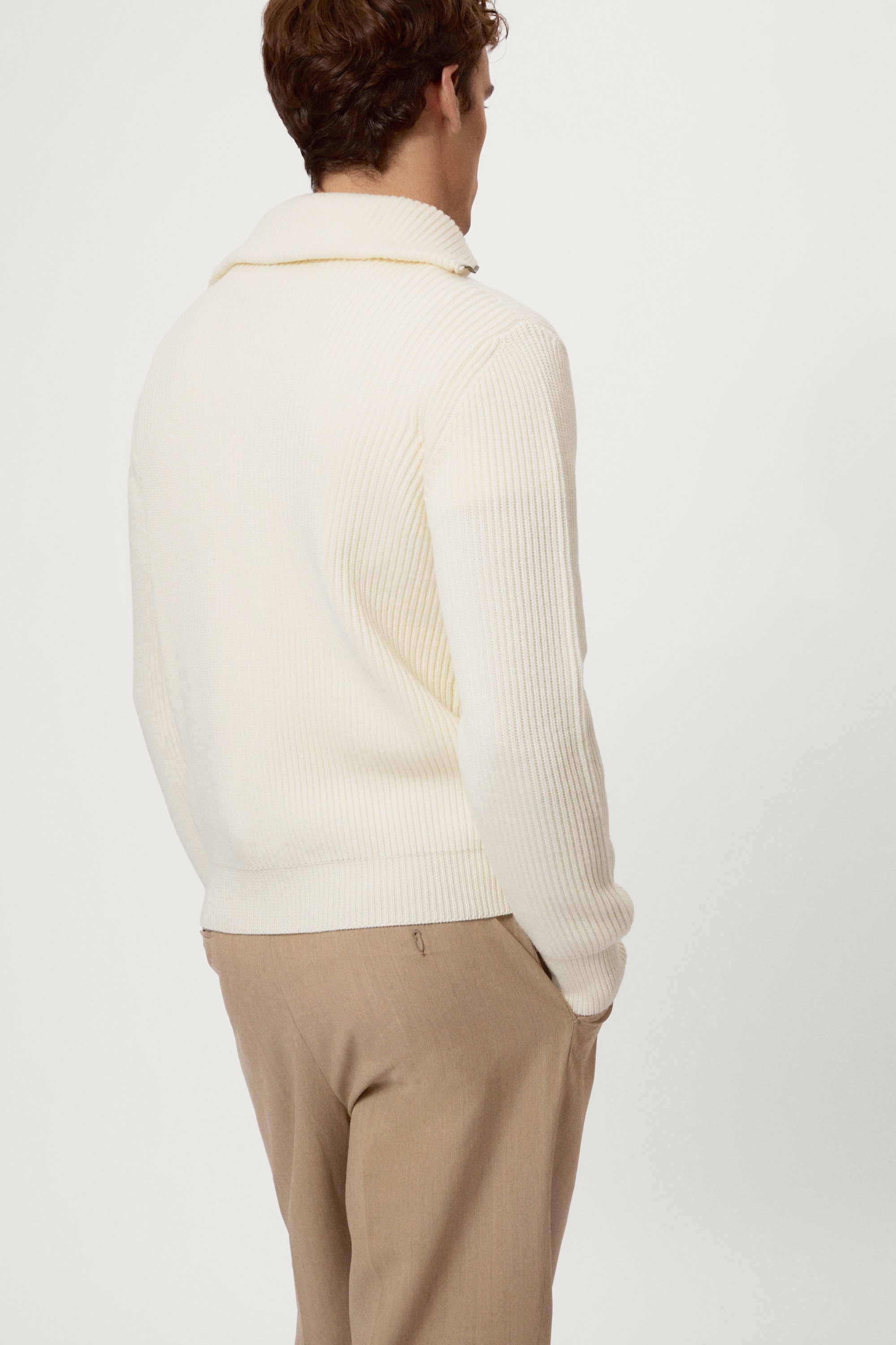 Man wearing a cream half-zip sweater against a white background