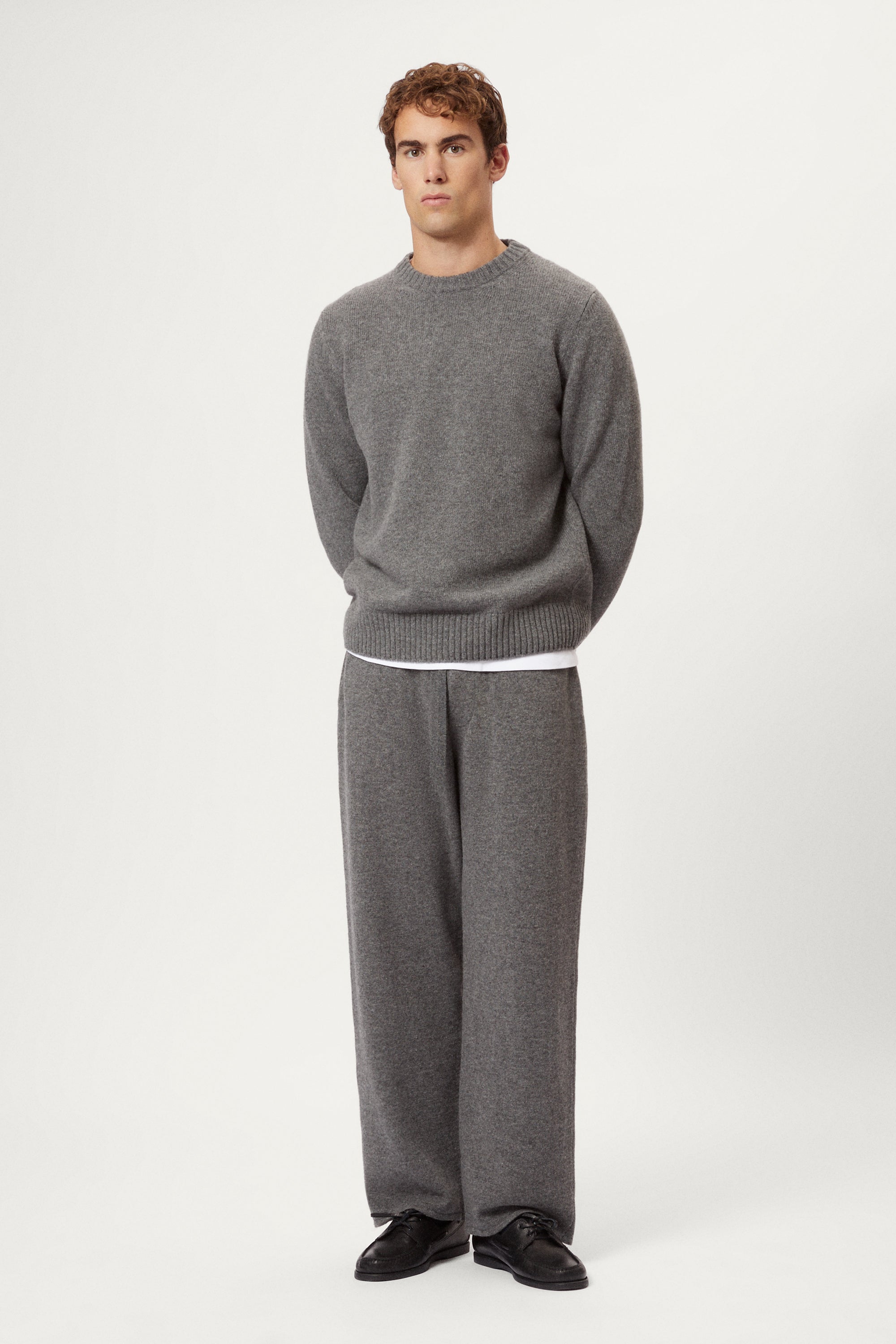 Person wearing a woolen gray knit pants and black shoes on a white background