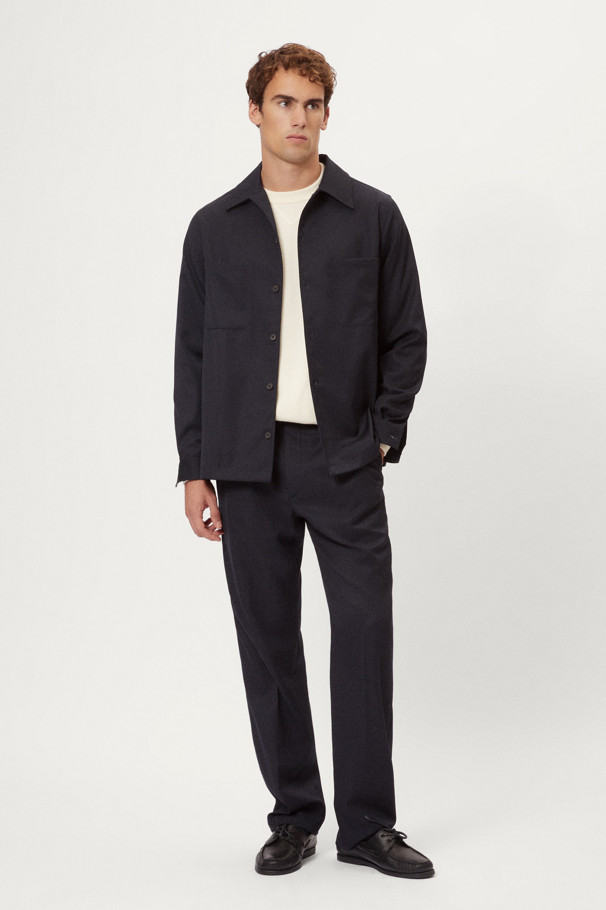 Man wearing a dark blue Twill Wool Overshirt over a white shirt on a light gray background