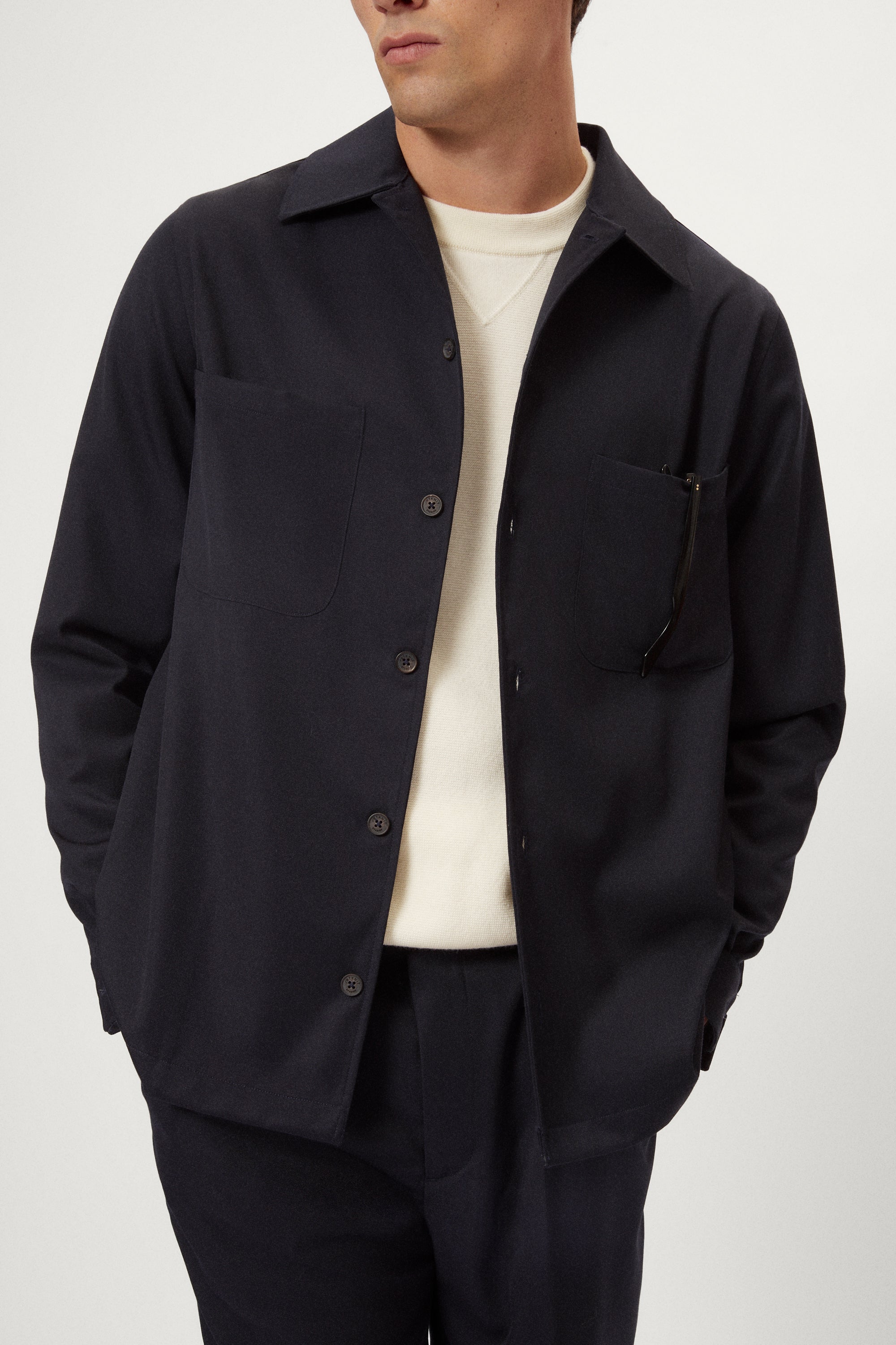 Man wearing a dark blue Twill Wool Overshirt over a white shirt on a light gray background