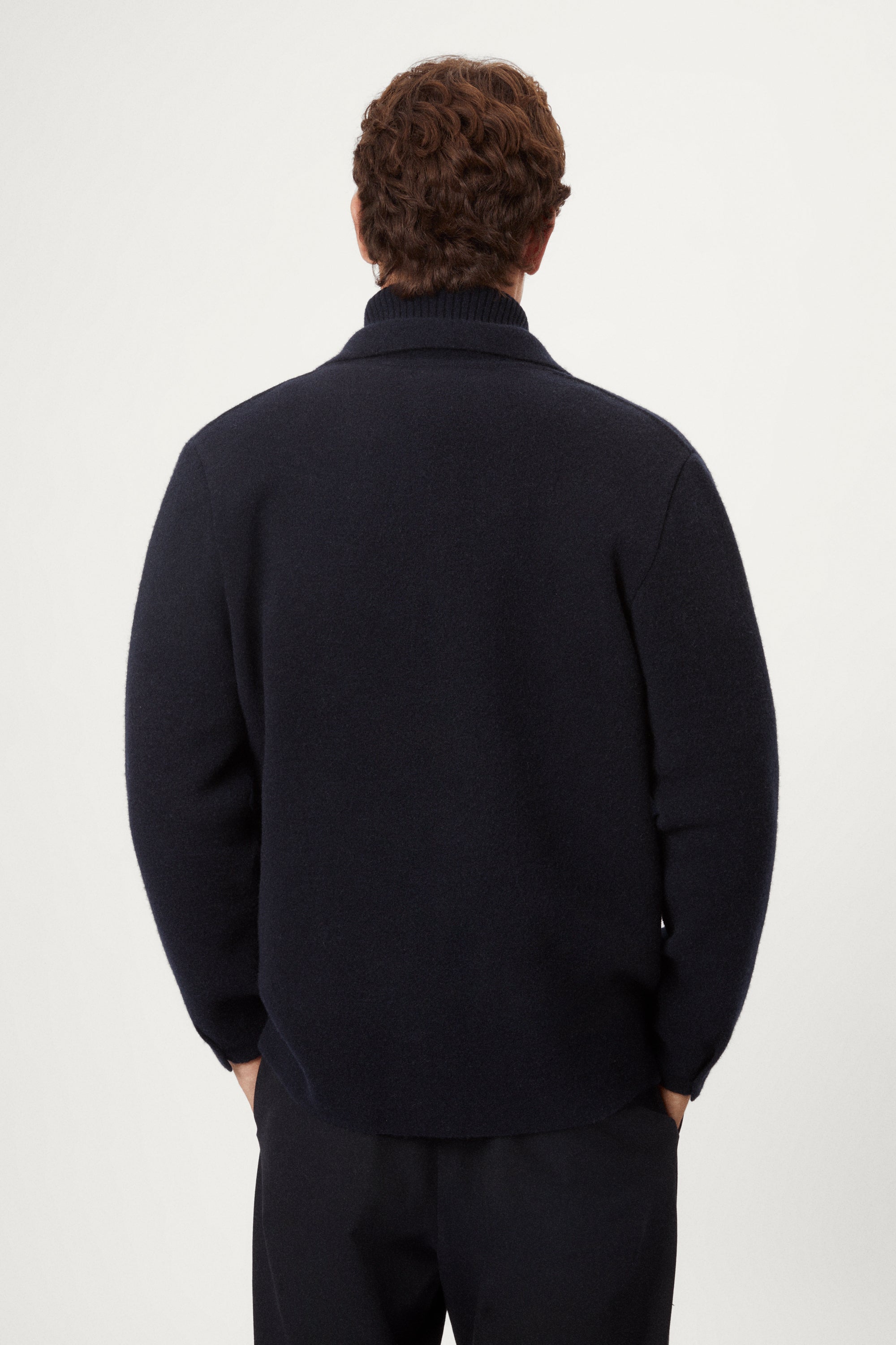 Man wearing a dark blue boiled wool jacket against a white background