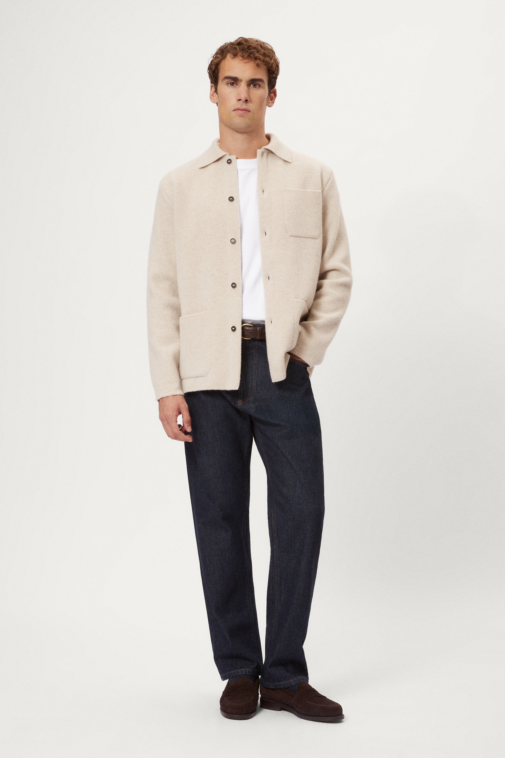 Person wearing a beige Boiled Wool Jacket over a knit sweater with a plain background