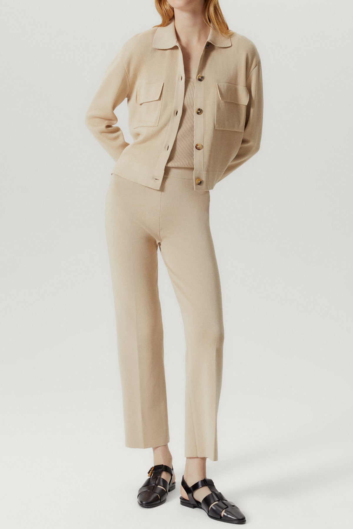 Person wearing a beige outfit with a jacket and pants on a white background